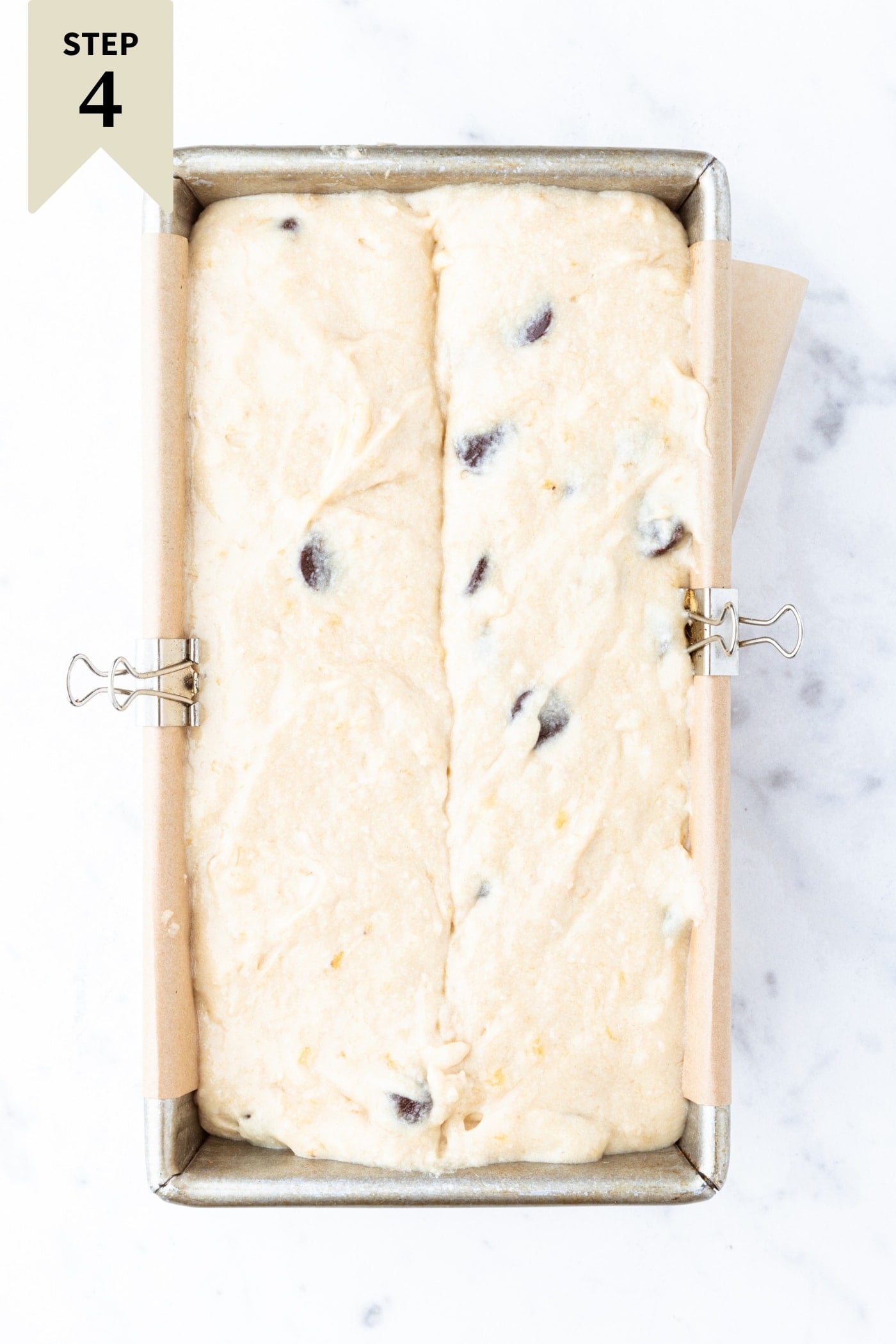 Unbaked loaf of chocolate chip banana bread resting on marble surface right before going into the oven.