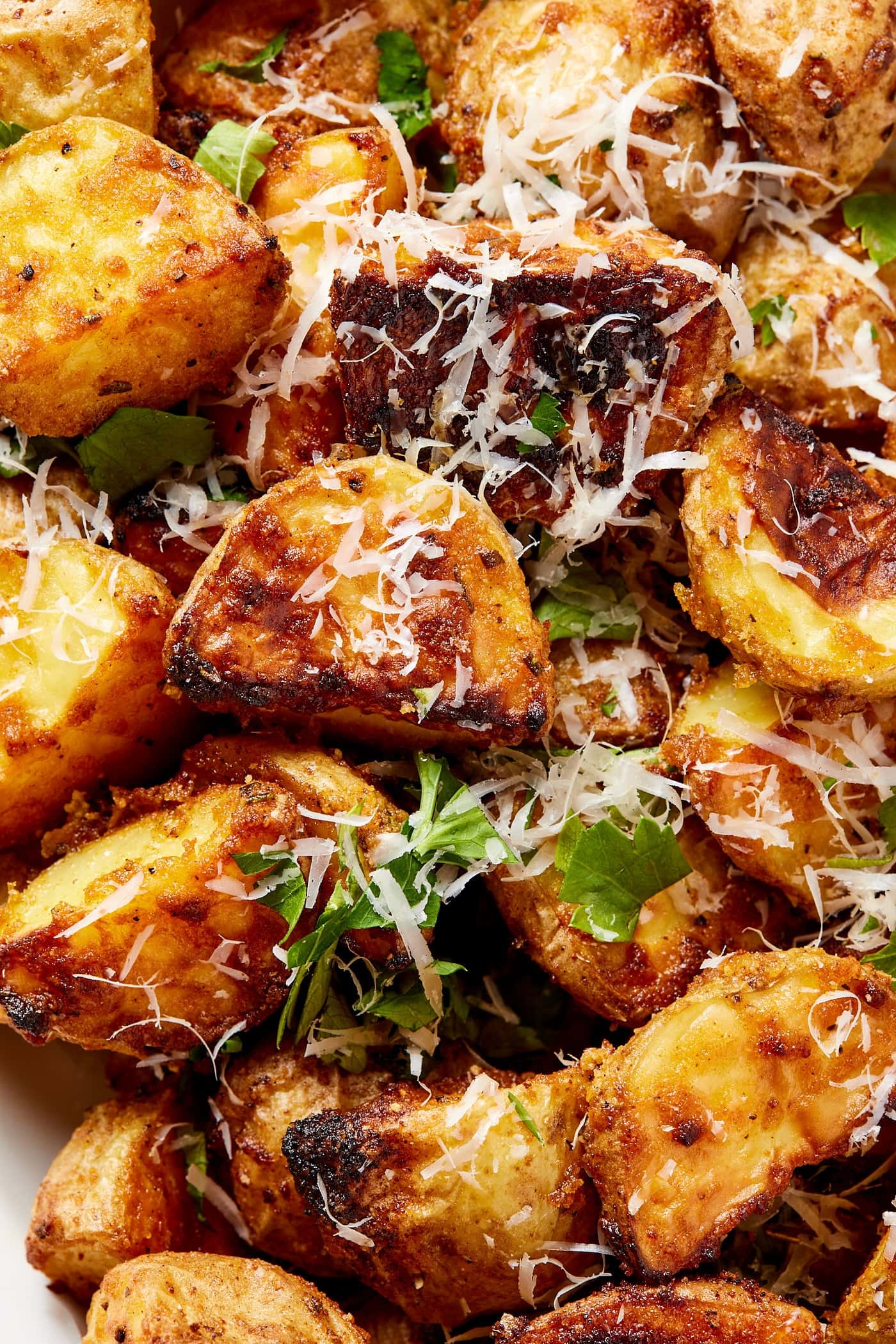 Crispy rosemary roasted potatoes topped with shredded cheese and fresh herbs right after coming out of the oven.