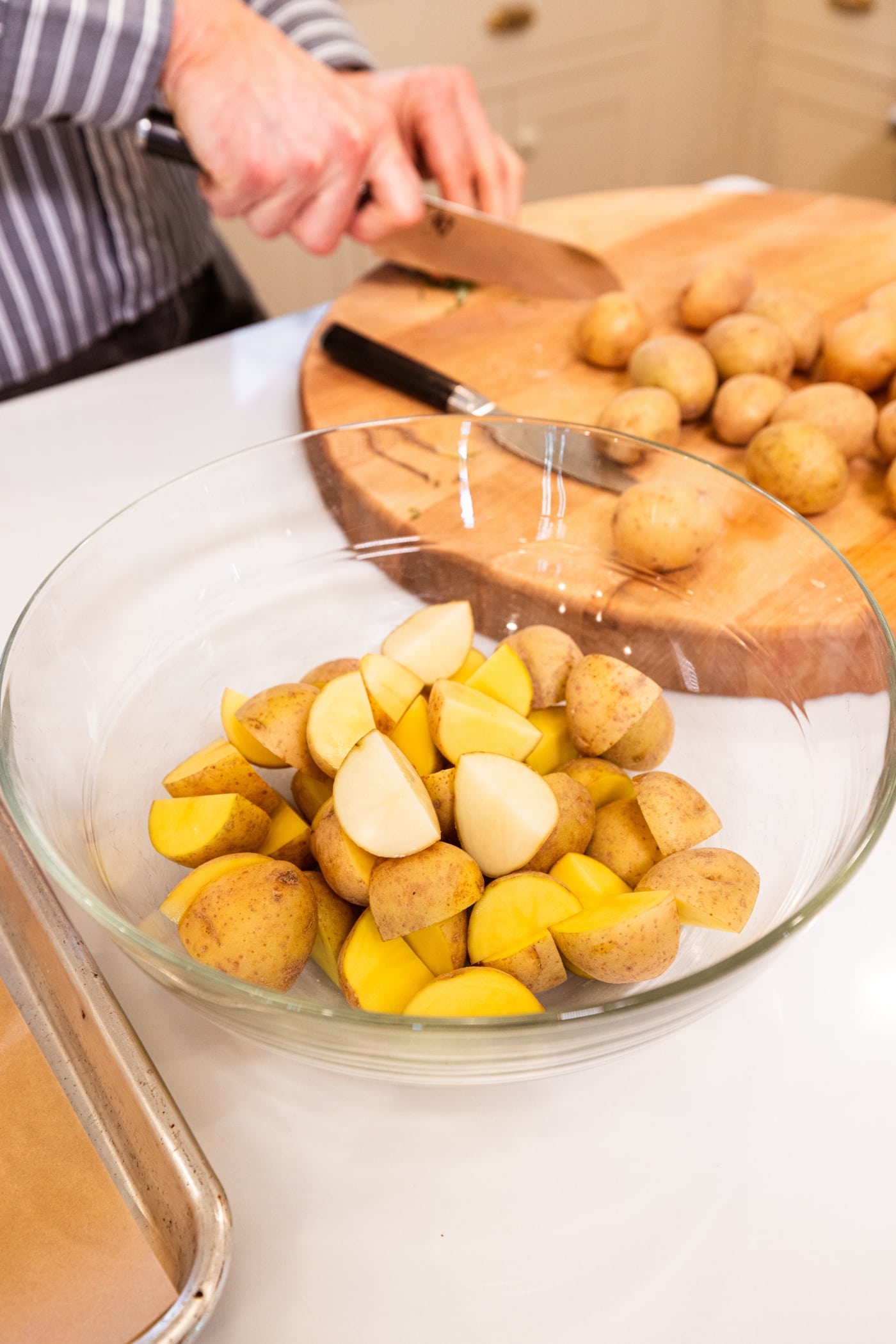 Glass bowl filled with sliced small potatoes for a rosemary roasted potatoes side dish.