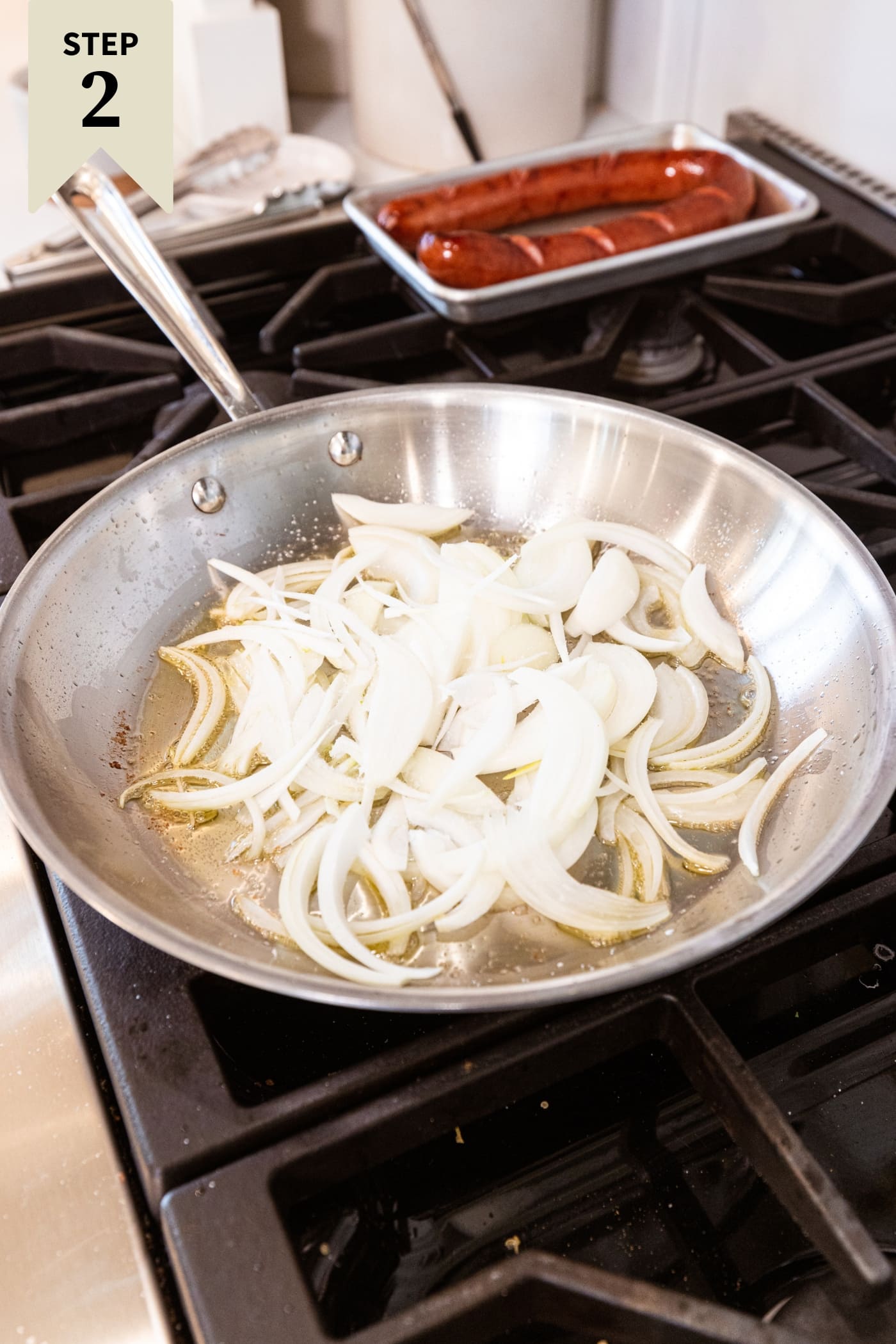 Metal skillet filled with uncooked onions in oil right after being diced.