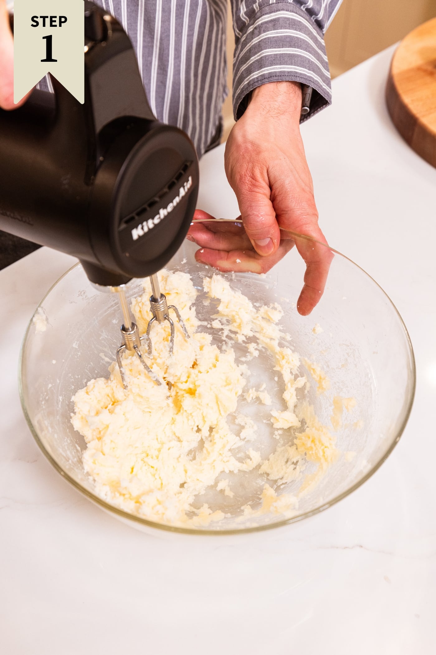 Glass bowl with wet ingredients being mixed together with a handheld mixer for a shortbread crust.