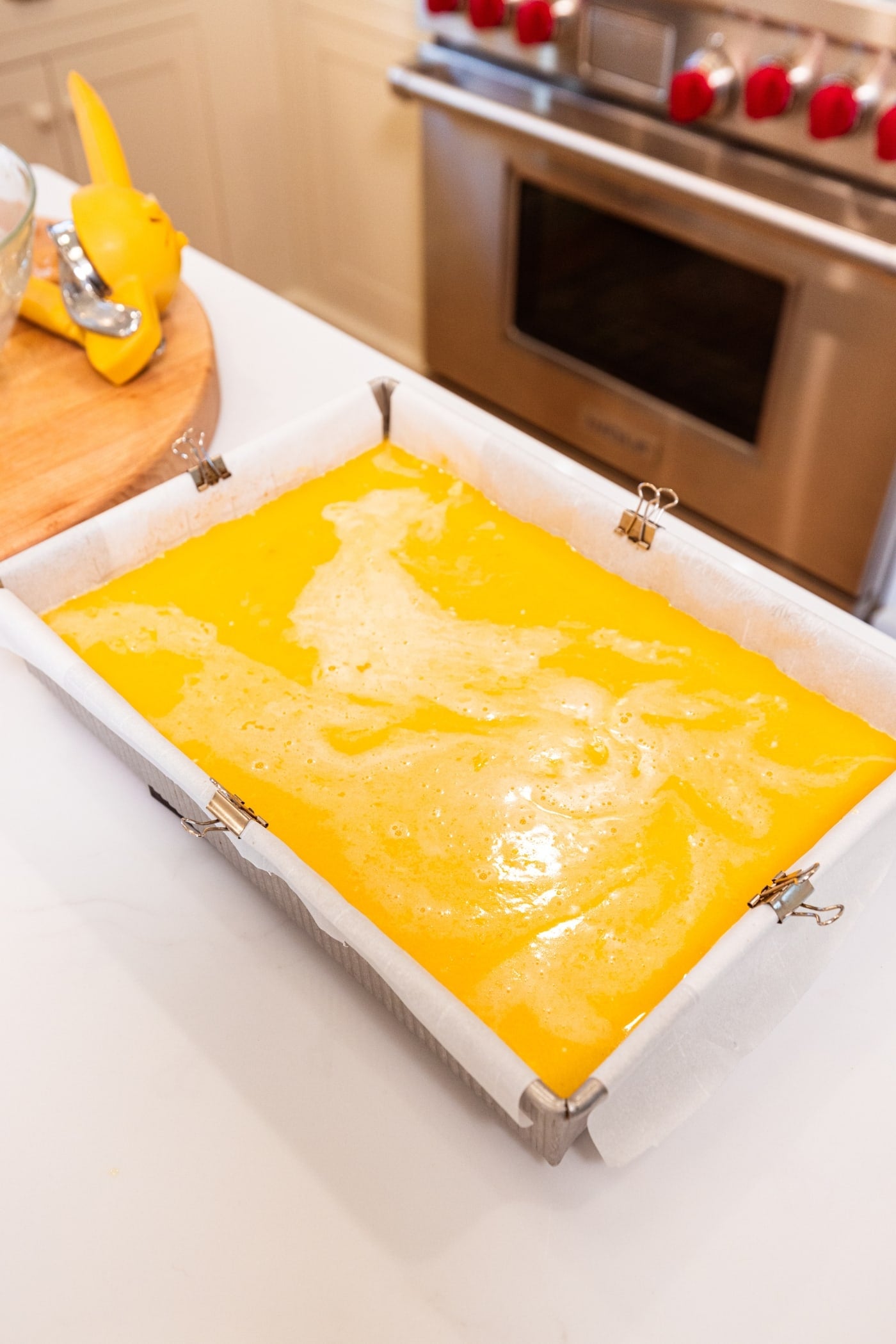 Rectangular baking dish filled with lemon filling to complete a lemon cheesecake bar before being placed in the oven to bake.