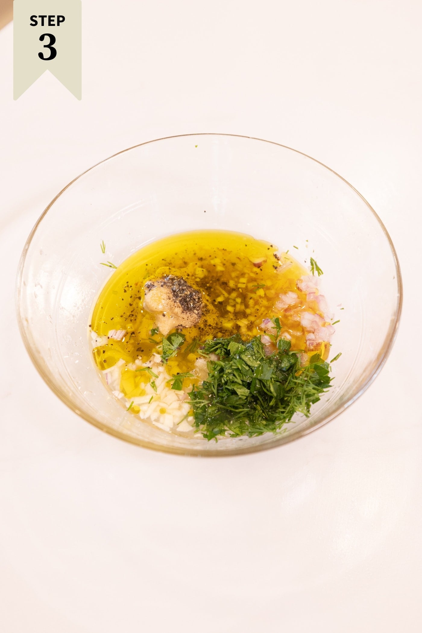 Glass bowl filled with ingredients needed for a lemon vinaigrette dressing.