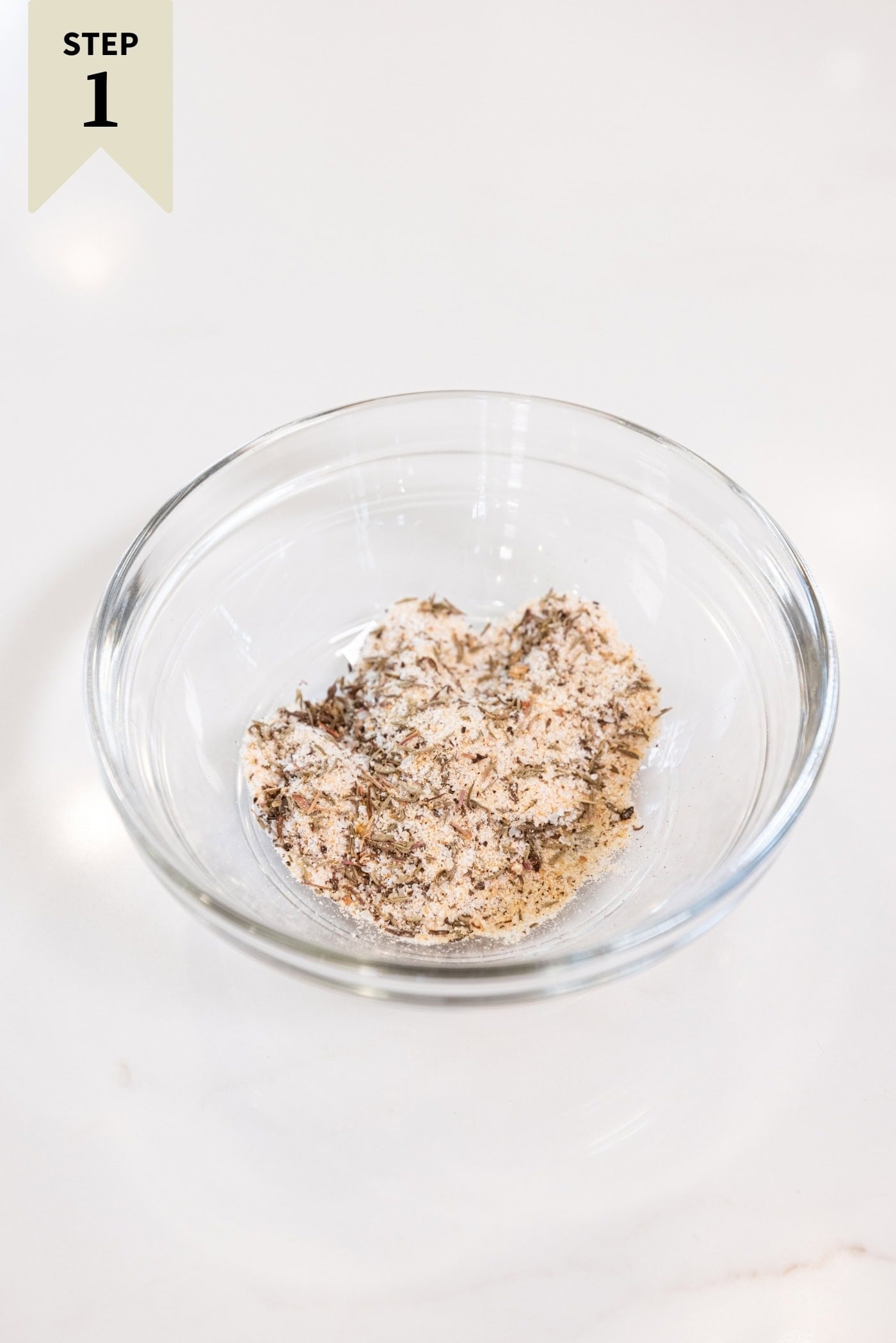 Small glass bowl filled with a dry rub to be added on top of raw chicken thighs to marinate them.