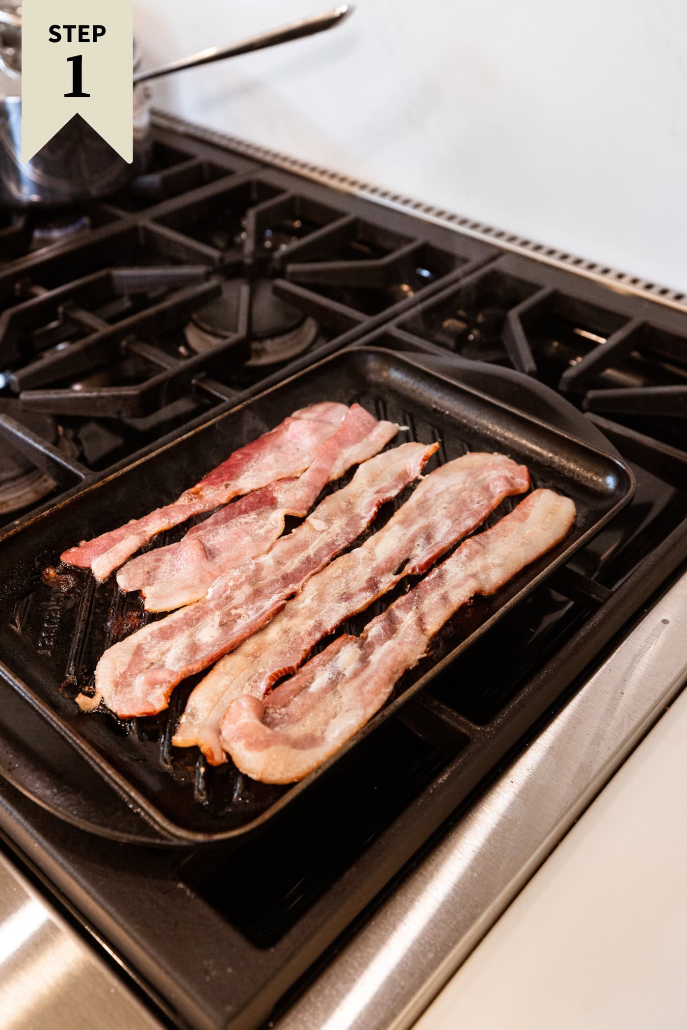 Grill pan on a stovetop with raw bacon cooking on the pan.