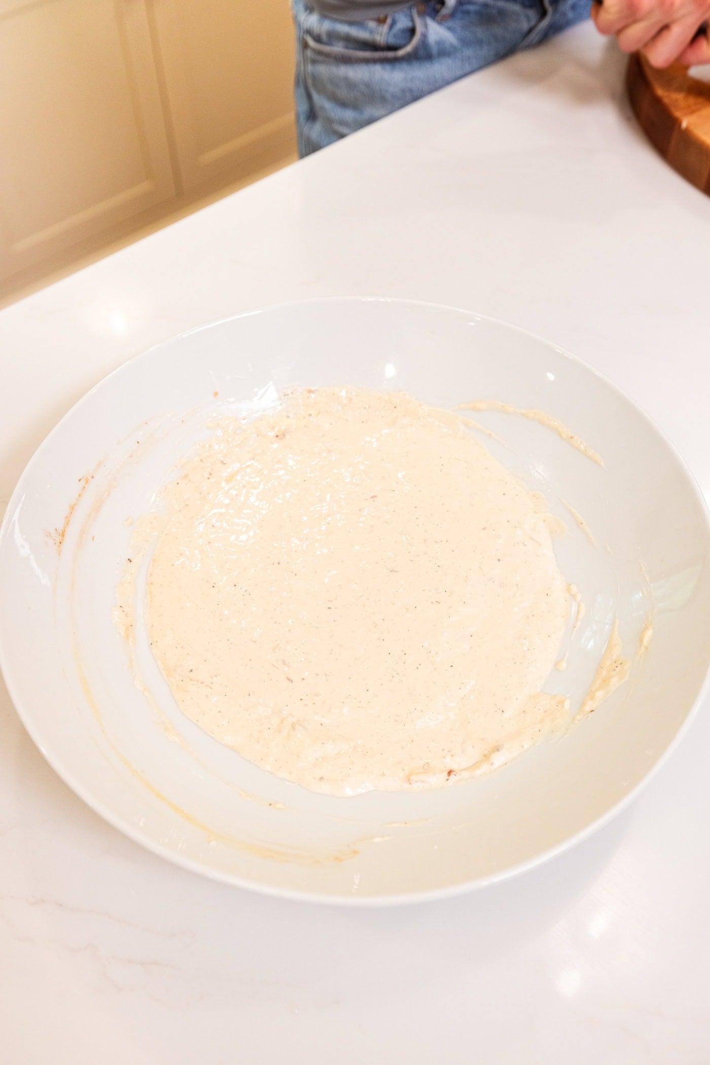 White-colored Caesar dressing in a large white bowl before pasta salad is added.