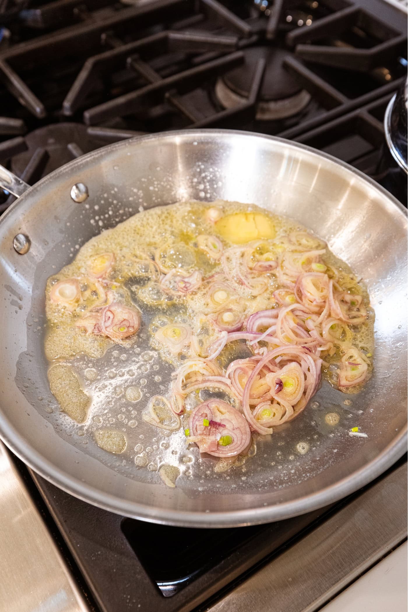 Butter in a skillet on the stovetop with scallion cooking in the butter.