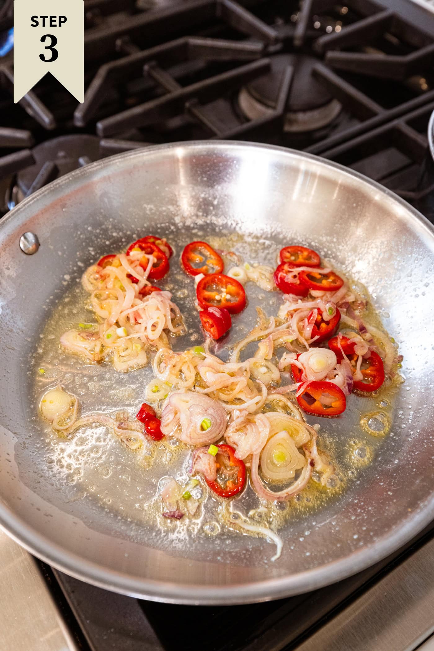 Skillet with butter, red chiles, and garlic cooking on the stovetop.