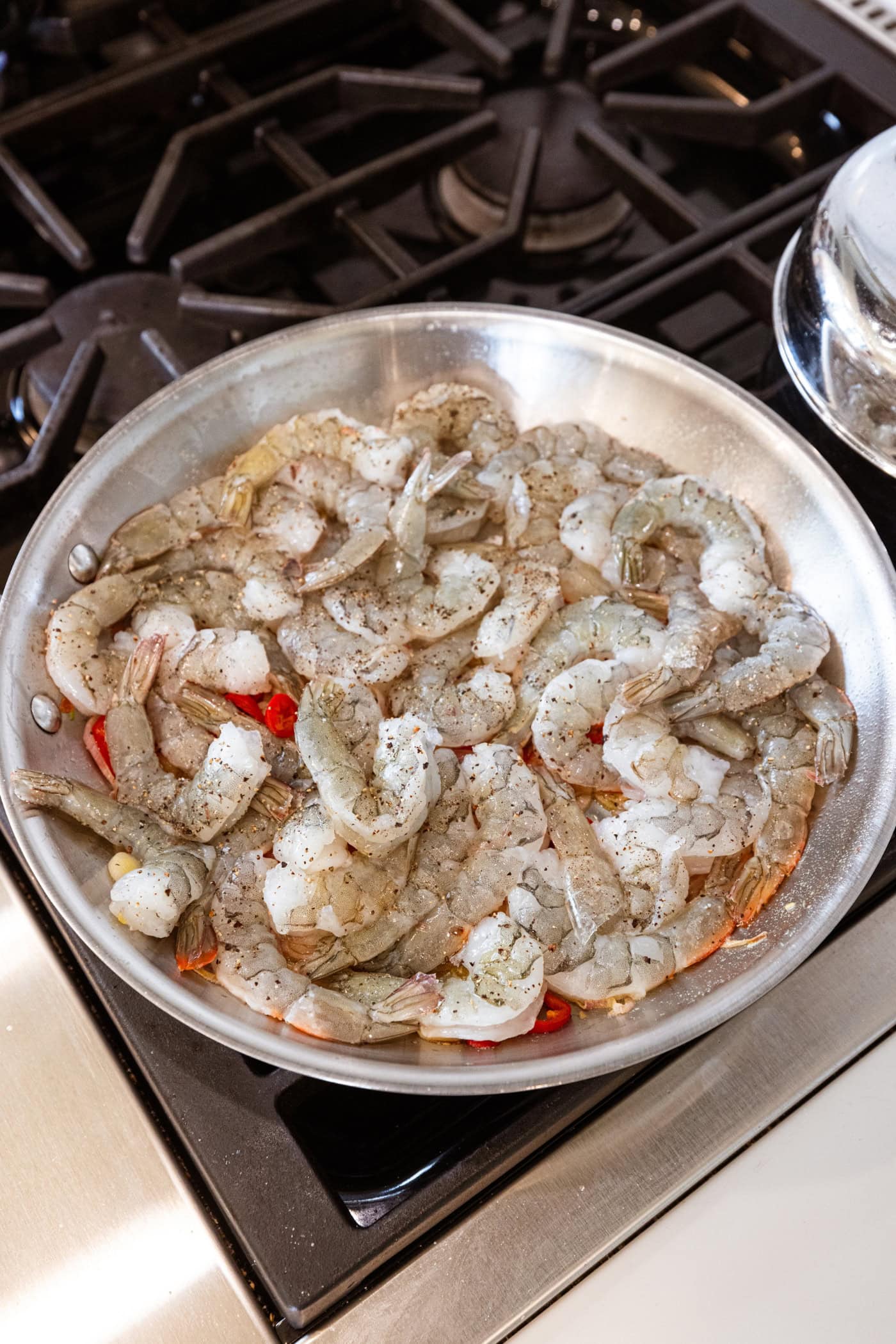 Raw shrimp cooking in a skillet on the stovetop for a garlic shrimp pasta recipe.