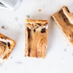 Three slices of peanut butter fingers showing chocolate and peanut butter swirls on marble surface.