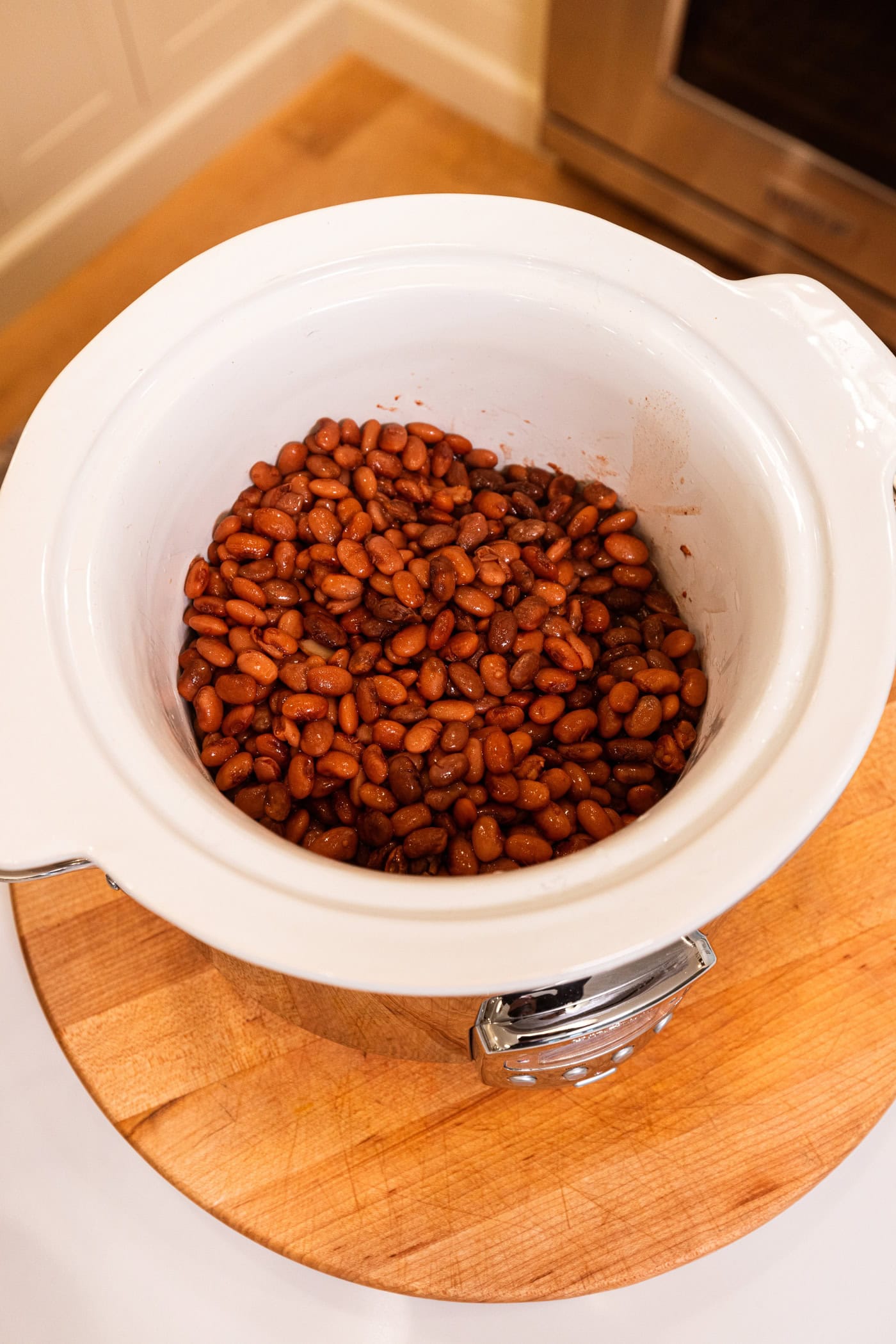 Slow cooker with cooked and drained beans with a brown color.