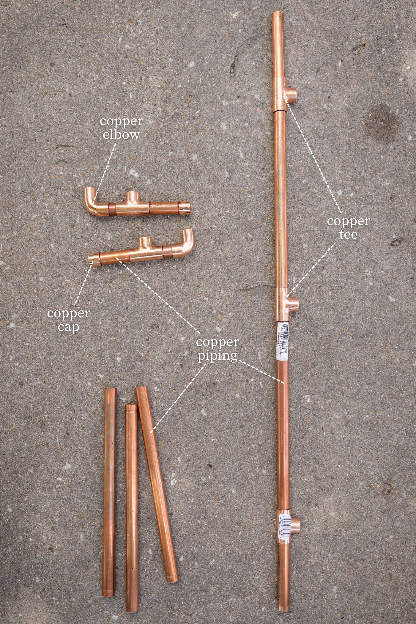 Copper pipe fittings needed for a DIY water fountain sitting on concrete surface.