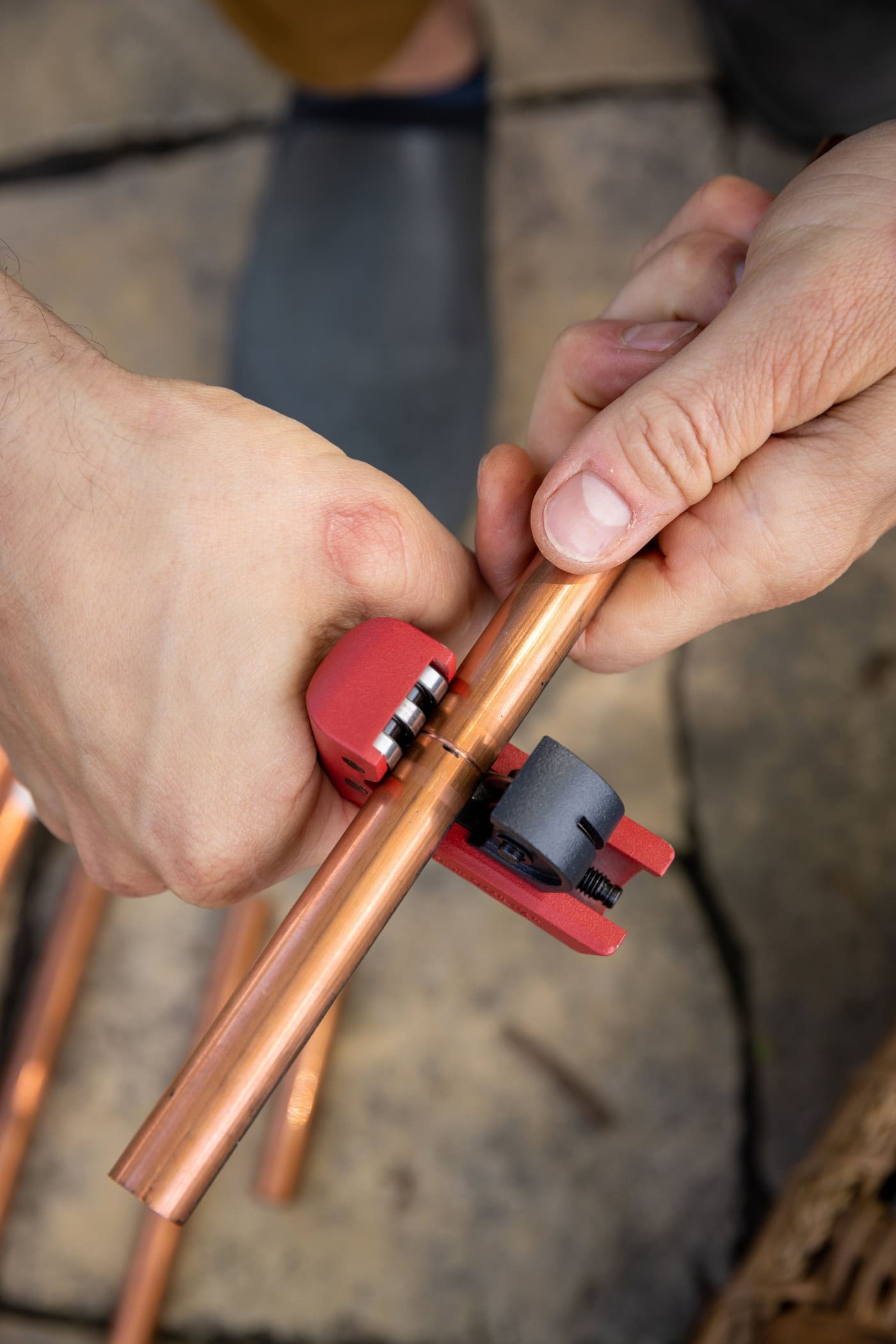 Hand using copper cutter to cut a copper pipe at a certain length.