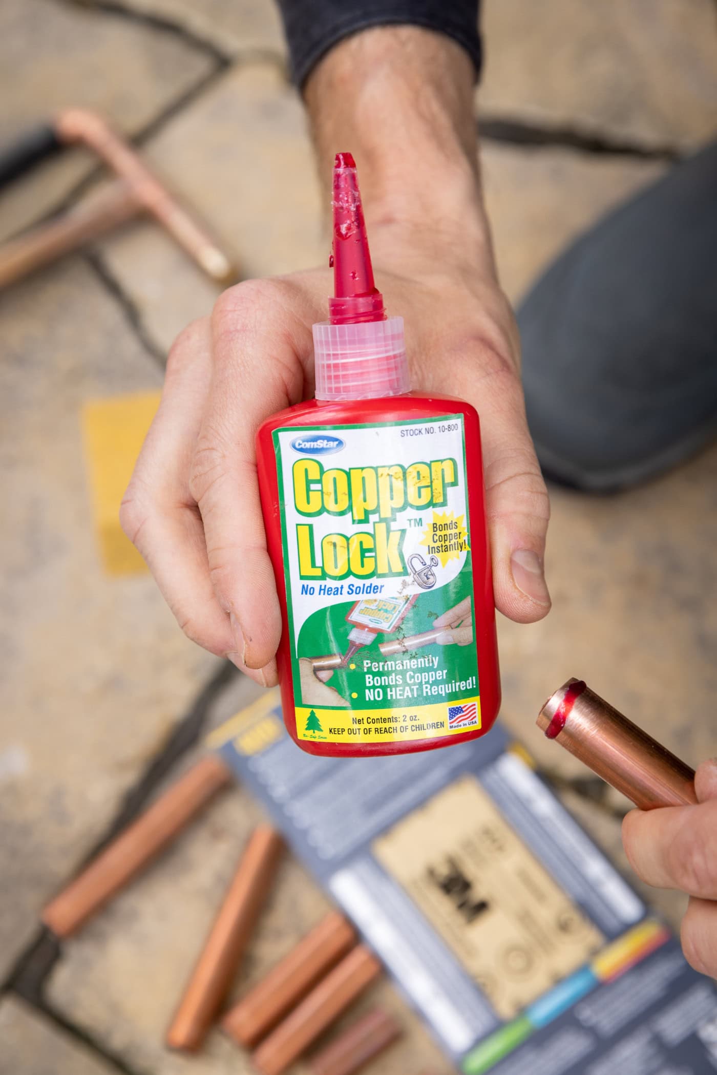 Bottle of "Copper Lock" with a red line of the liquid around the end of a copper pipe.