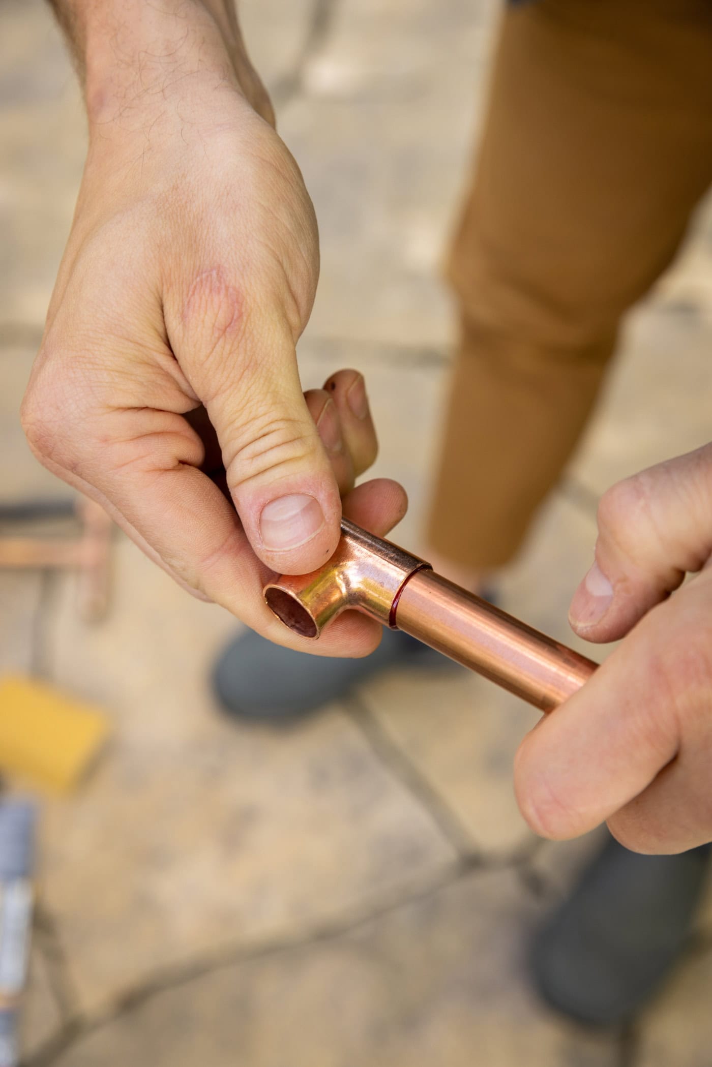 Hand fitting part of copper pipe onto another copper pipe to form a T.