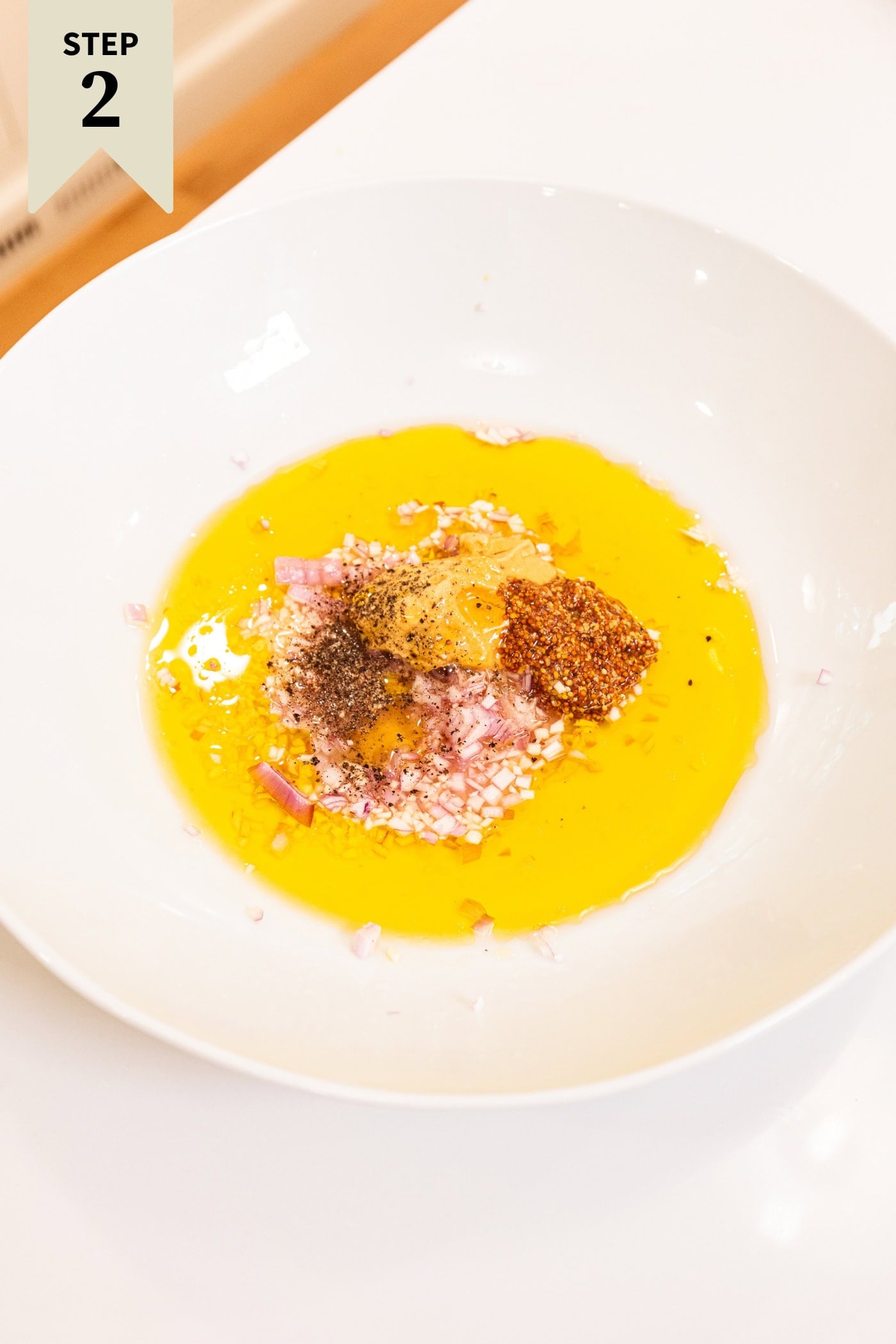 Large white serving bowl with ingredients needed for a mustard-based vinaigrette.