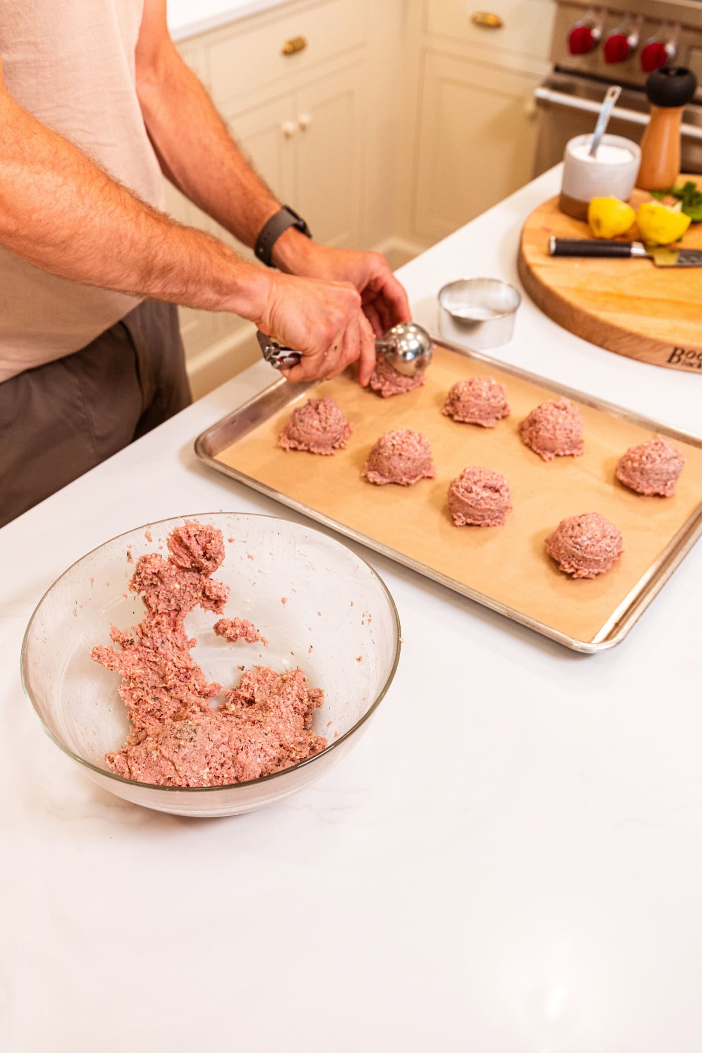 Parchment-lined baking sheet filled with scoops of ground turkey for turkey burgers.