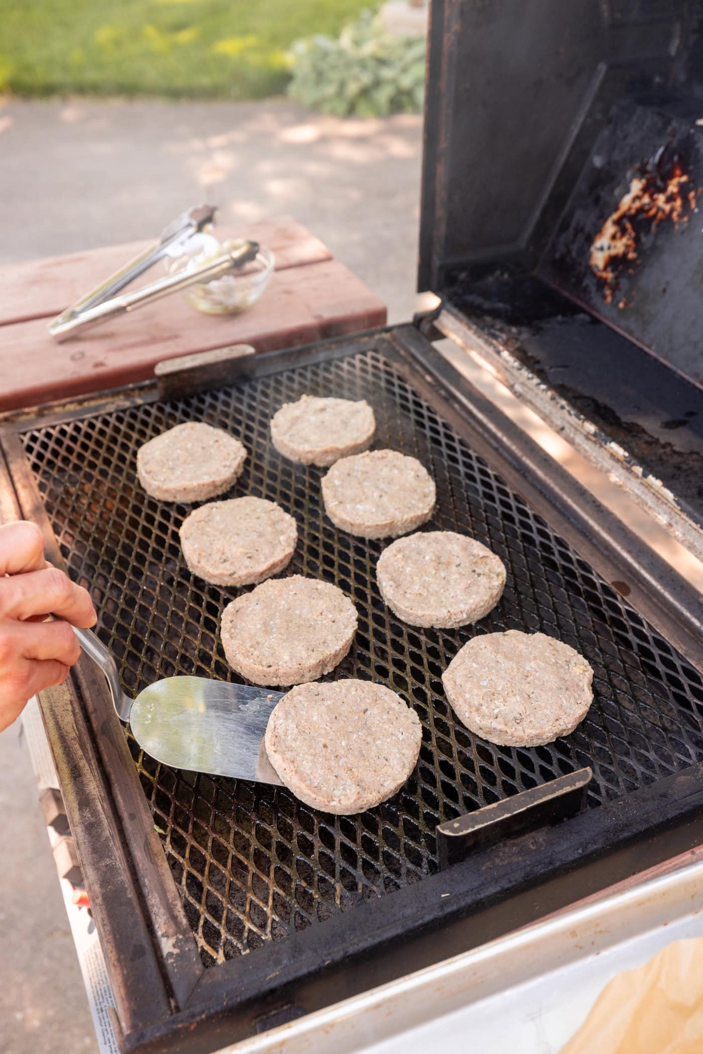 Raw round turkey burger patties sitting on the grates of a grill.