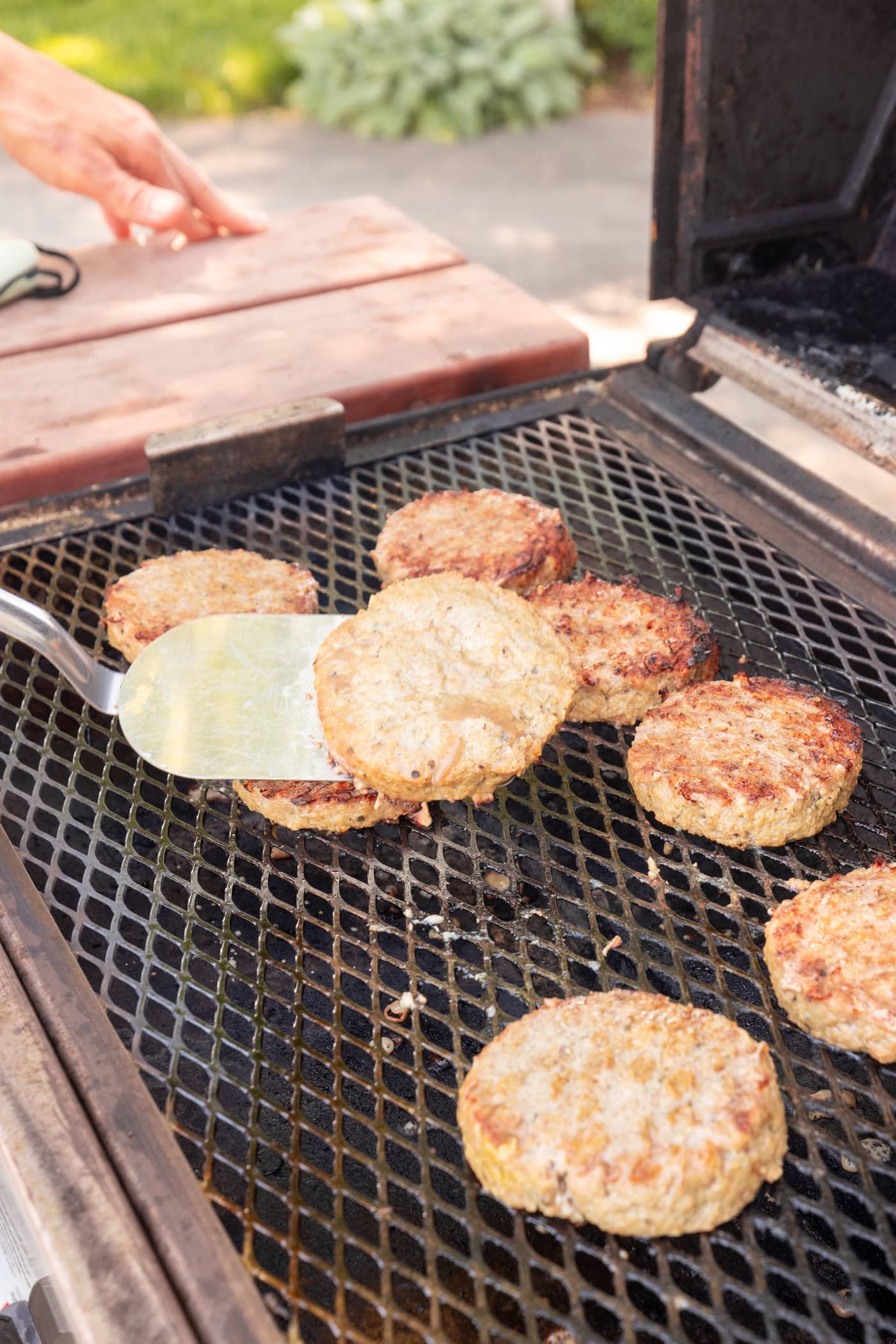 Grilled Greek turkey burgers grilling on grates on a grill with browned charred texture.