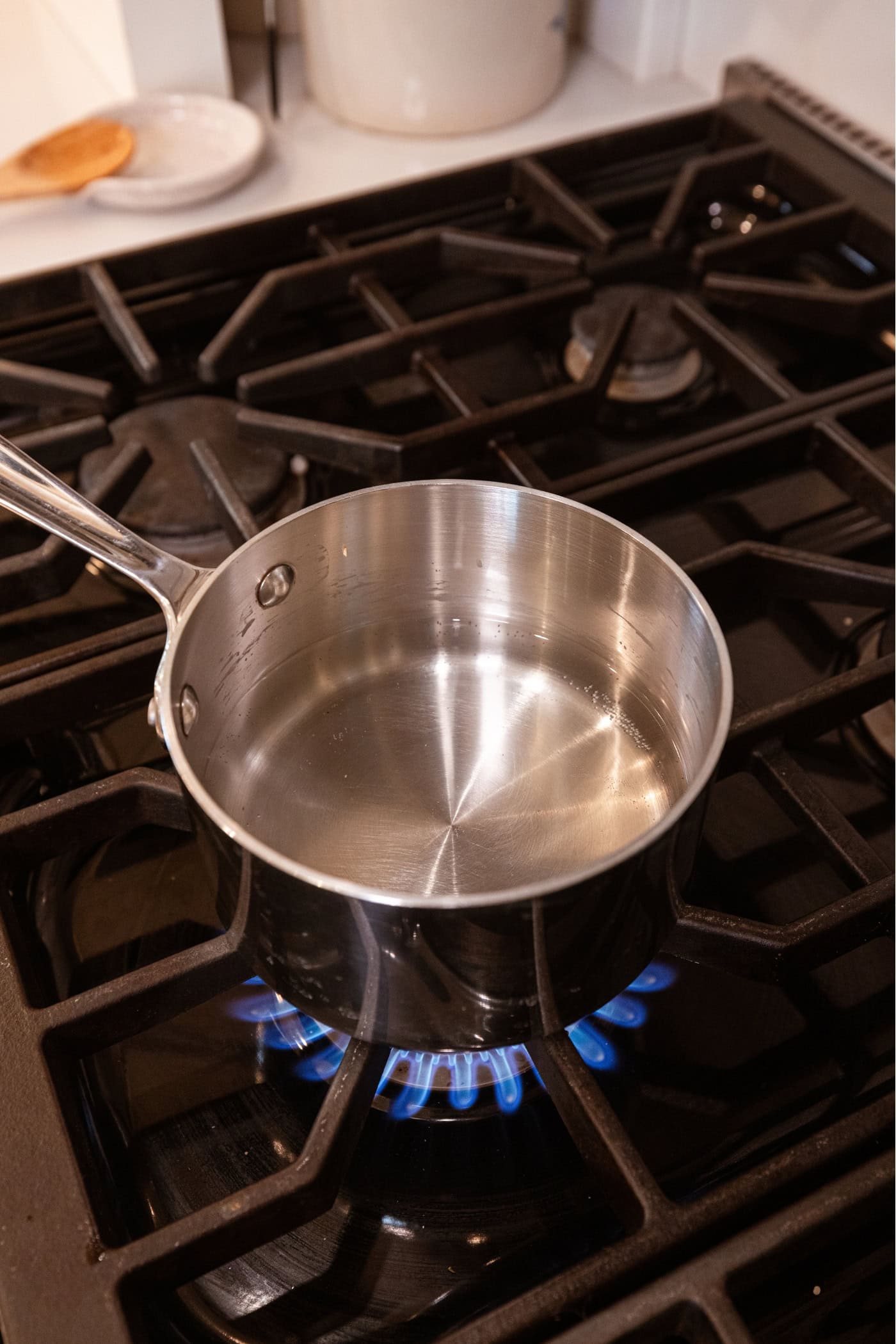 Small saucepan sitting on stovetop with clear vinegar brine inside.