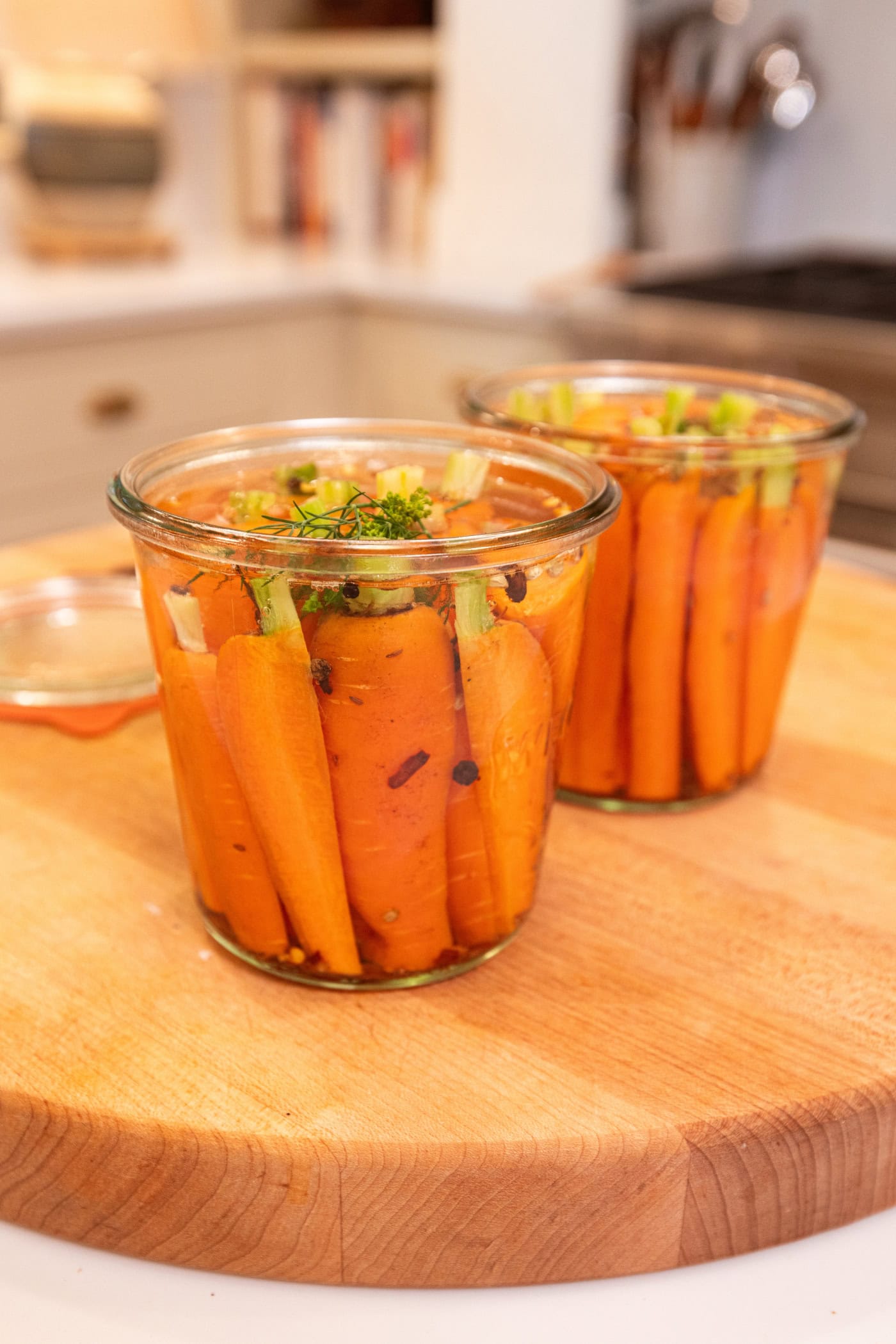 Quick pickled carrots sitting in glass pint jars with brine on top.