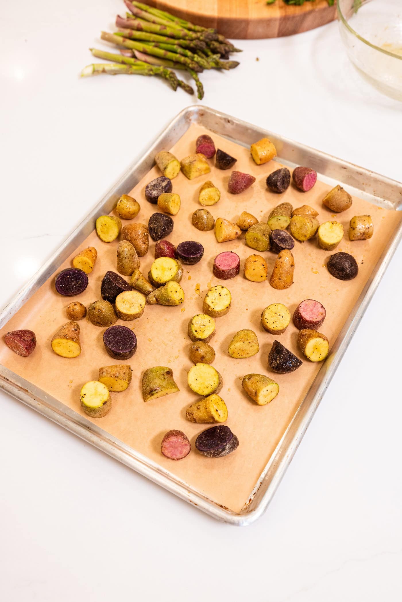 Sheet pan with piece of parchment paper with sliced potatoes tossed with spices and olive oil after roasting.