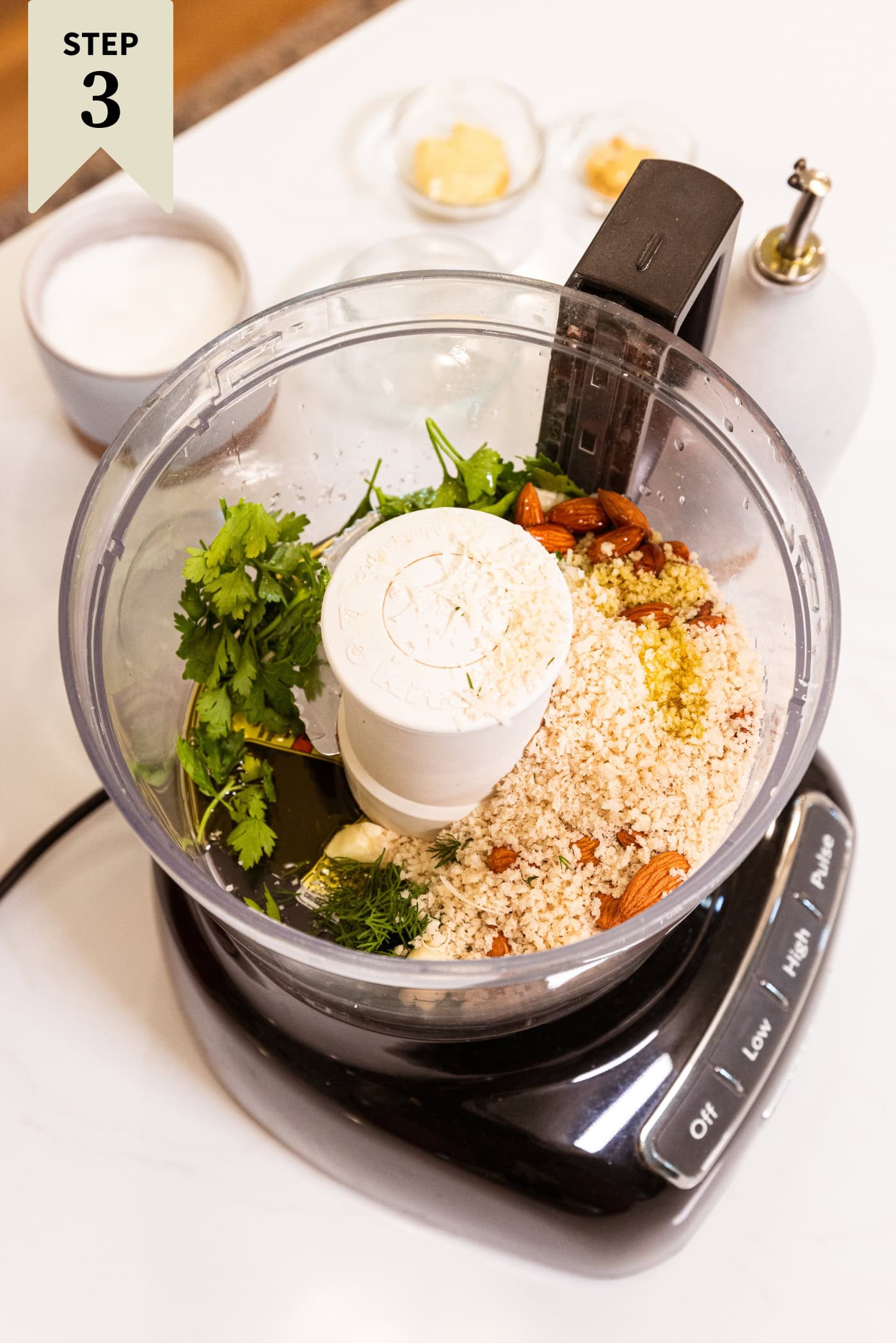 Food processor with ingredients needed to make an herb crust for baked halibut before being mixed together.