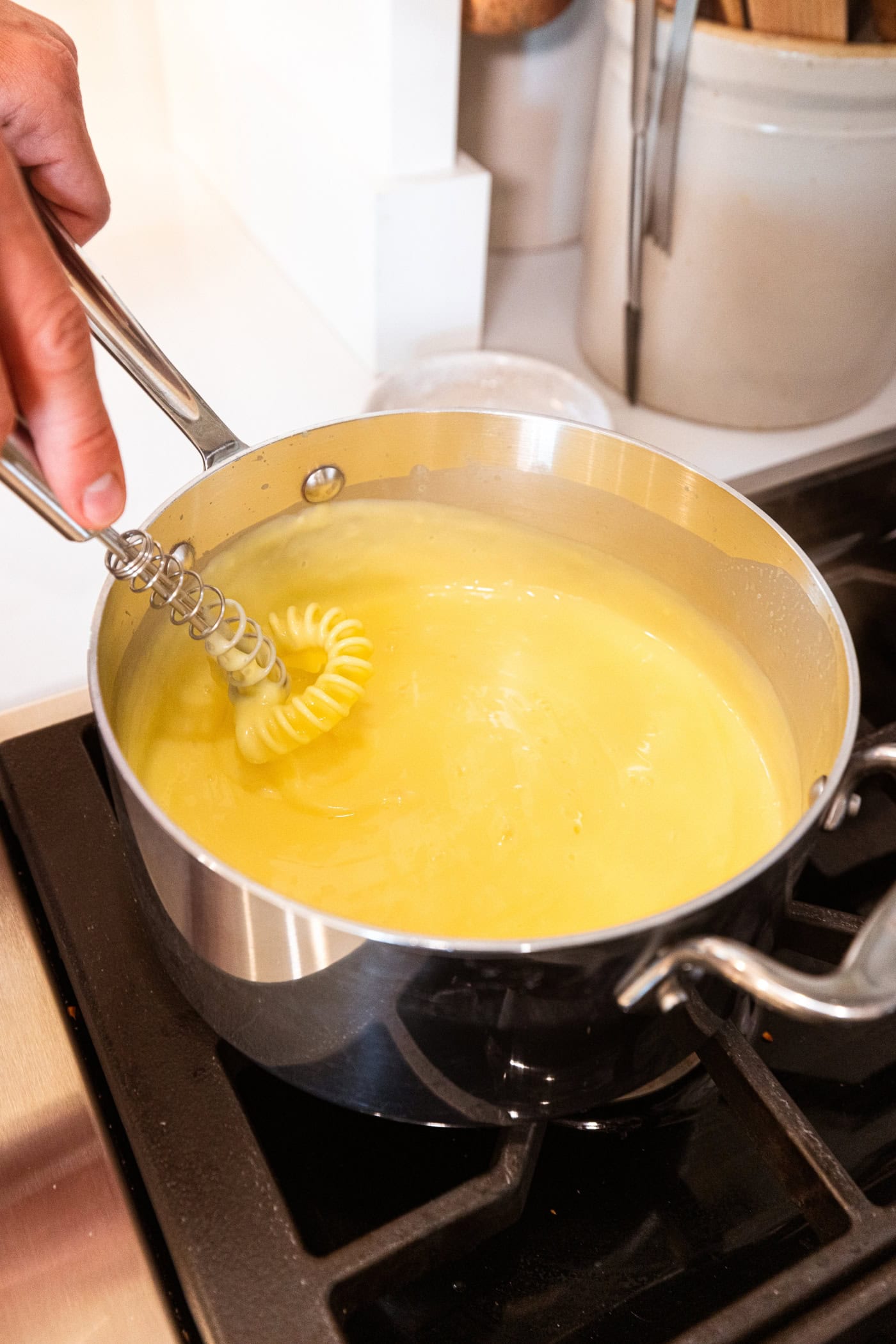 Medium saucepan on stovetop with mixture for vanilla pudding.