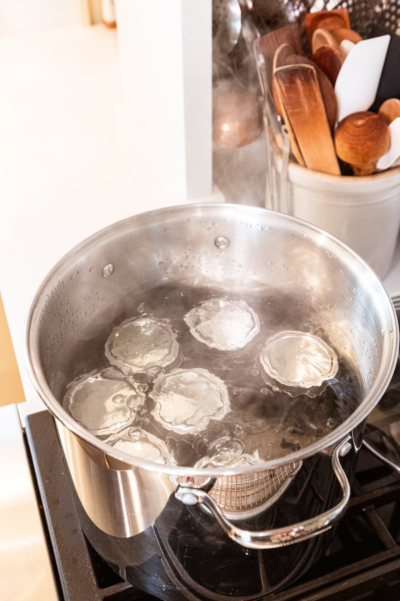 Large kettle filled with boiling water with jam jars boiling in canner.
