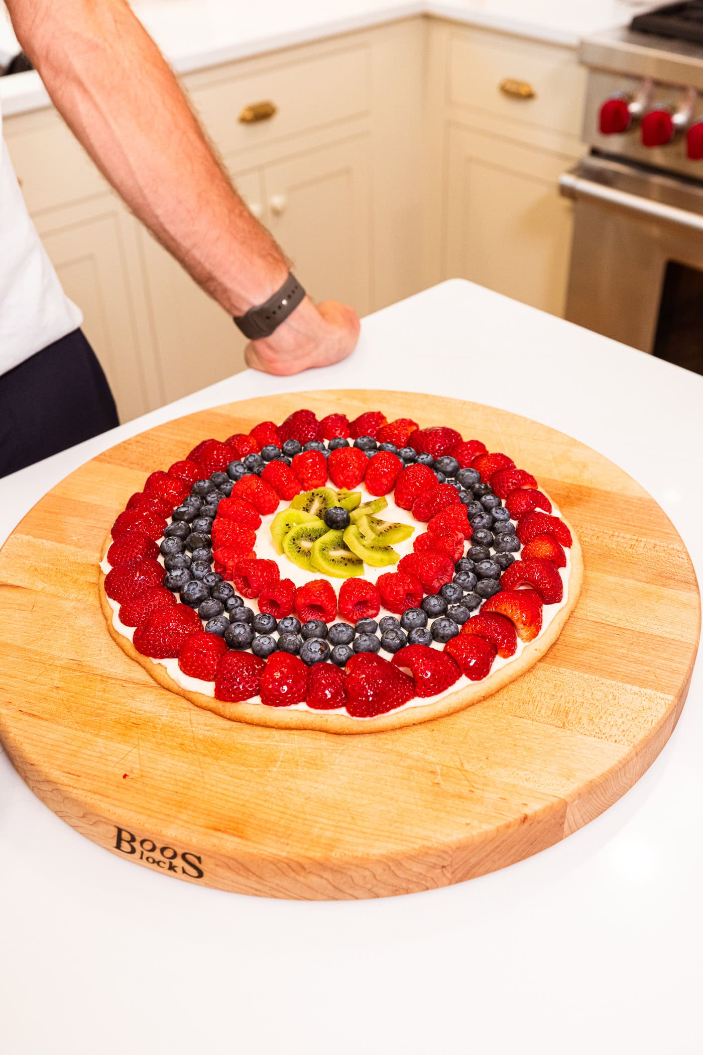 Fruit pizza removed from baking dish with rings on fruit on top.