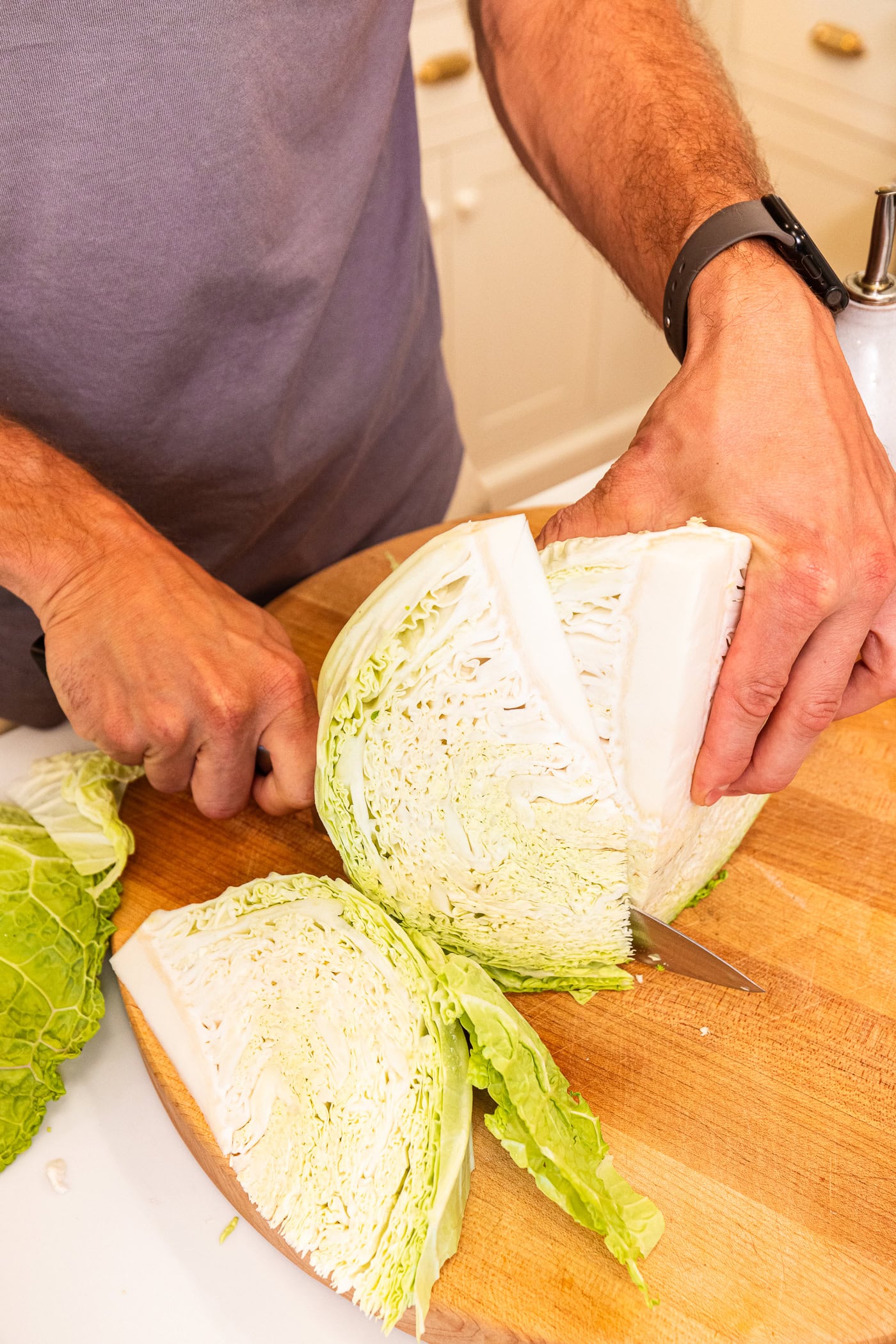 Wedges of cabbage sliced into pieces on wooden cutting board.