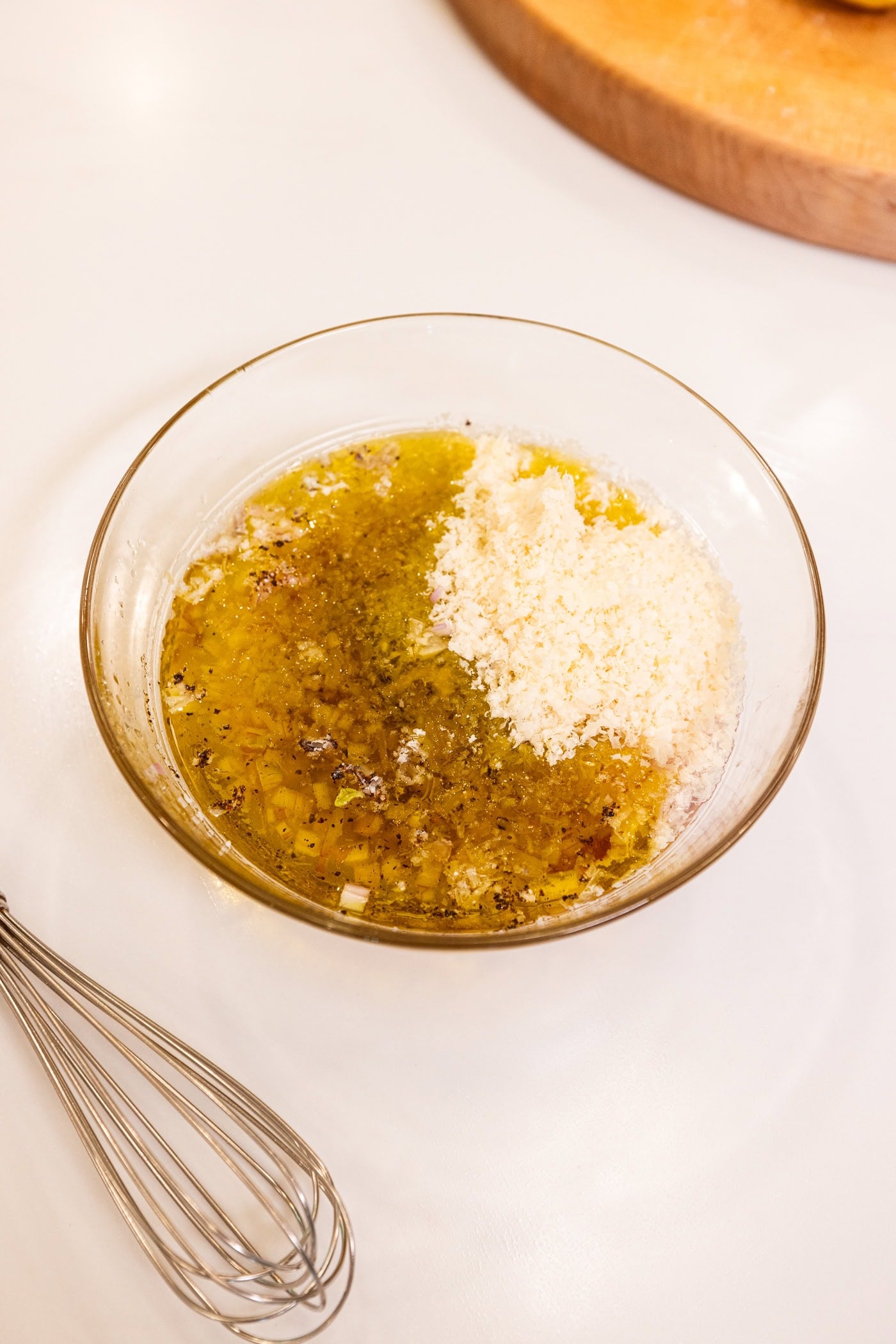 Glass bowl filled with ingredients needed for a Parmesan dressing for a salad before being mixed together.