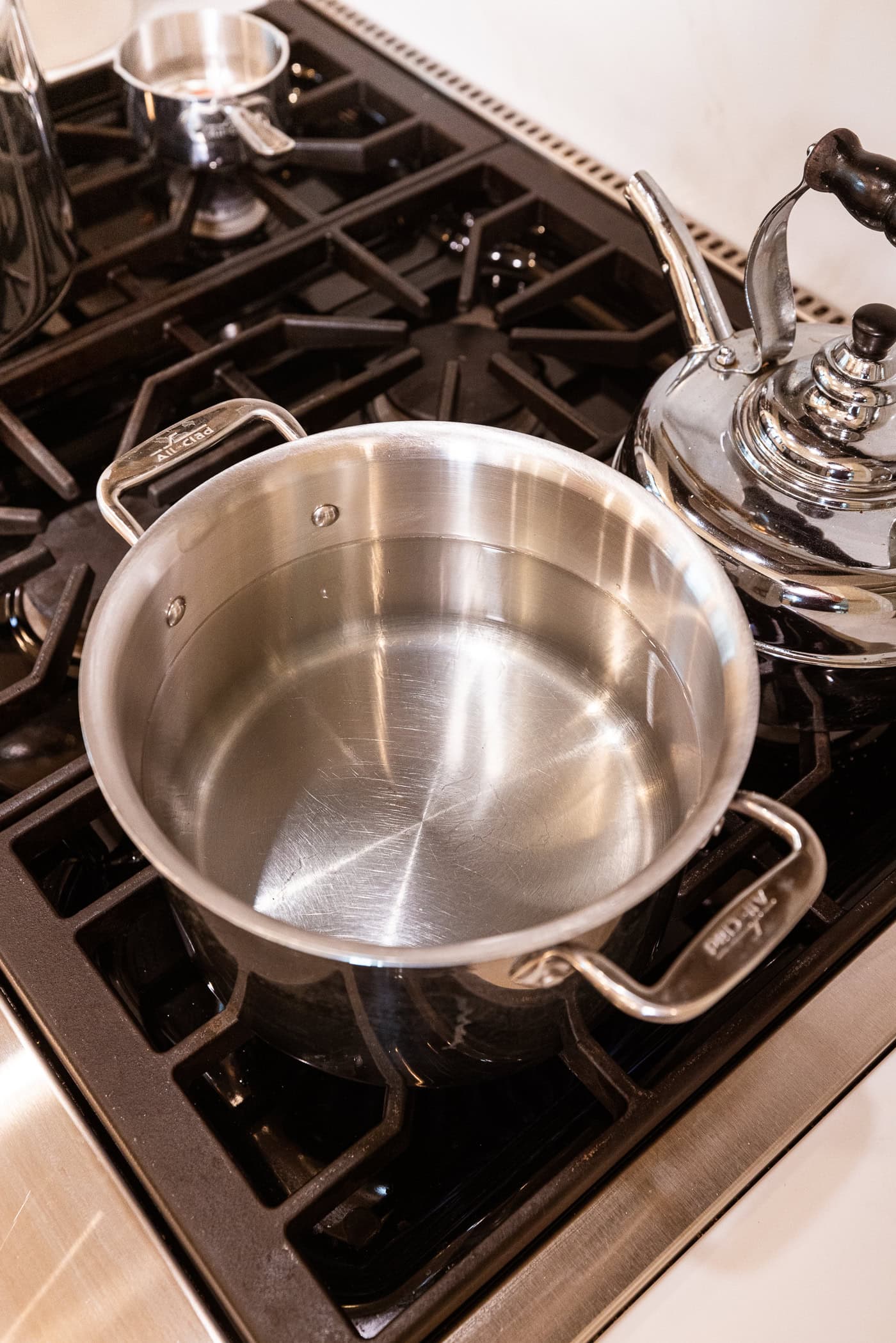 Large metal pot sitting on the stovetop with brine for pickles heating up.