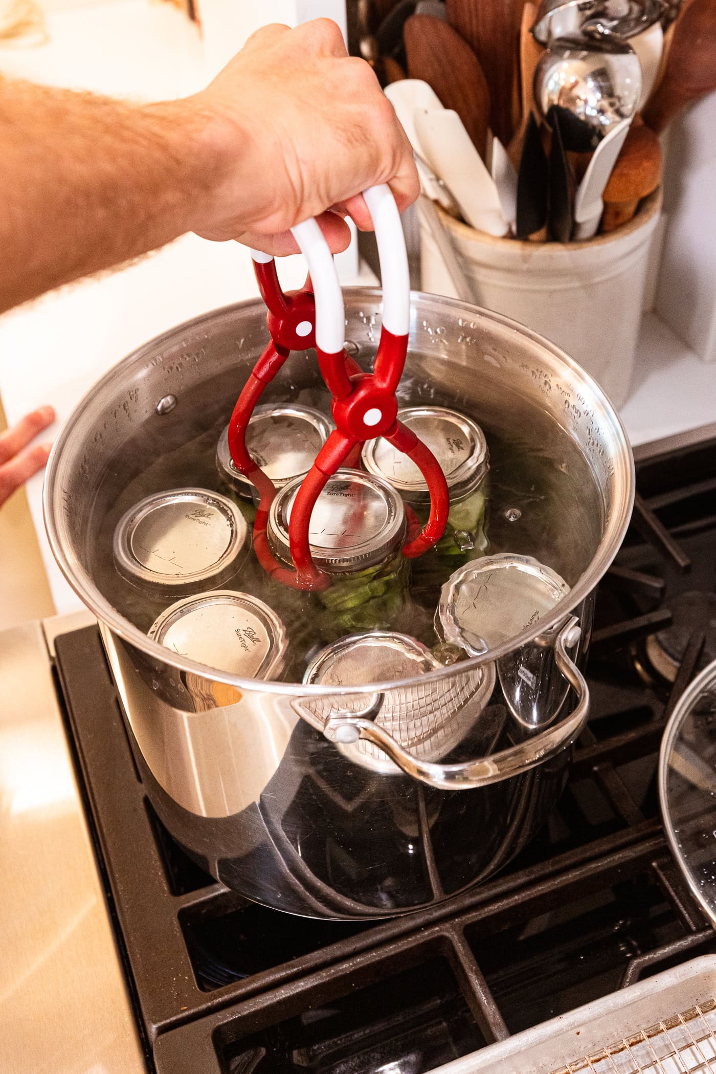 Jar lifter putting jars of dill pickles into a water bath canner to be canned.