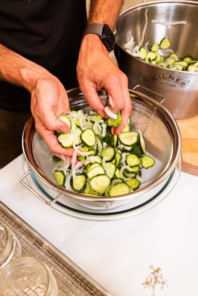 Draining liquid from cucumbers and onions in a colander.