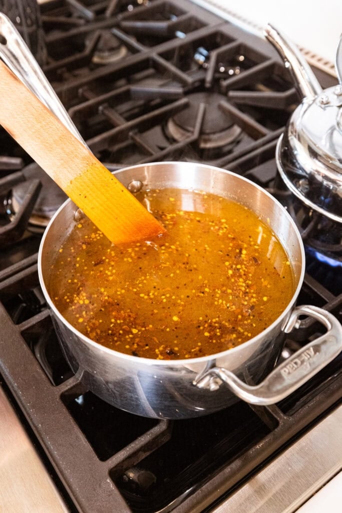 A pickle brine in a pan sits on the stove simmering.