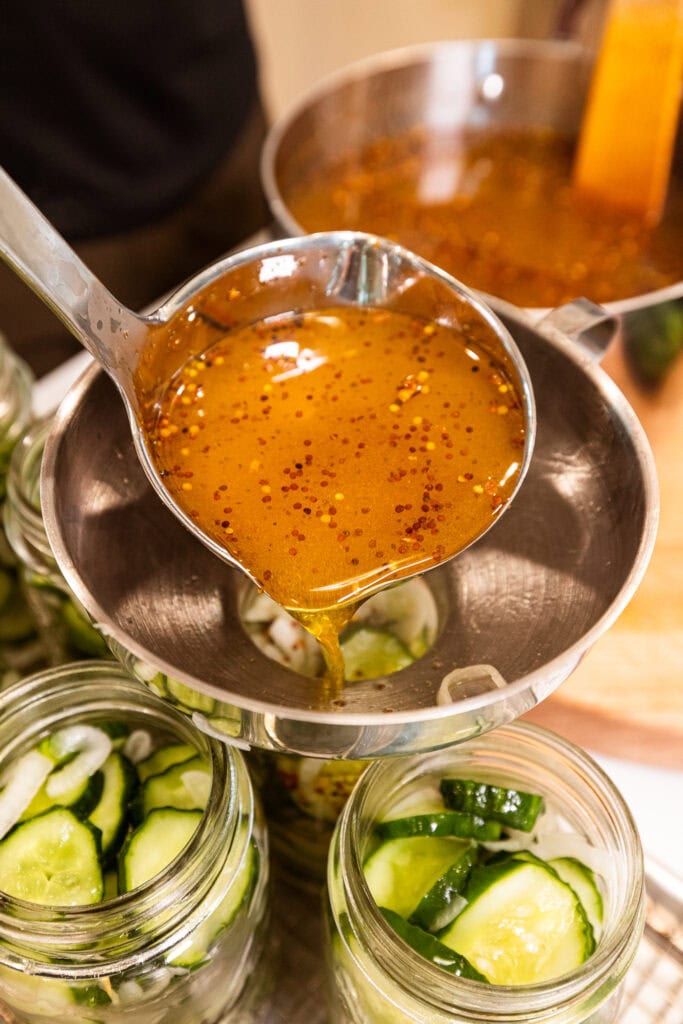 Ladling brine into a jar full of pickles.