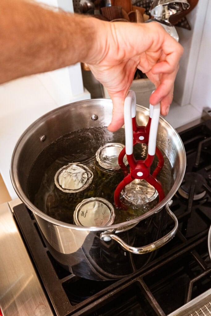 Setting a jar into a pot of boiling water to seal.