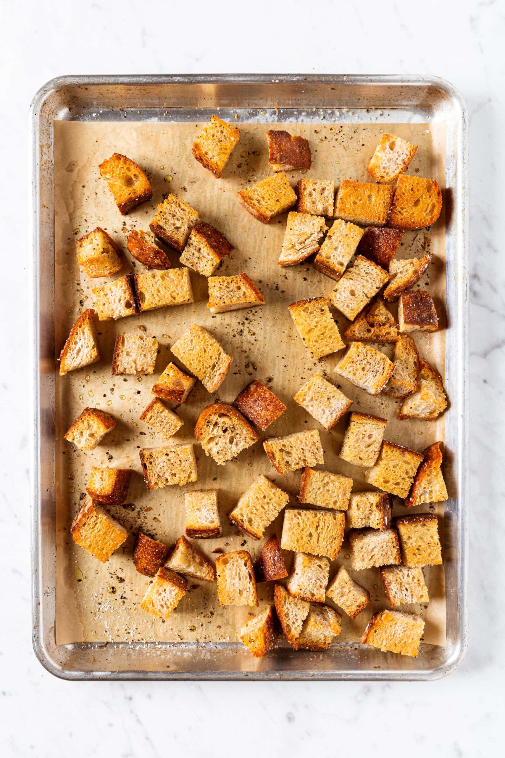 Sheet pan with bread cubes with toasty crusted exterior right after coming out of the oven.