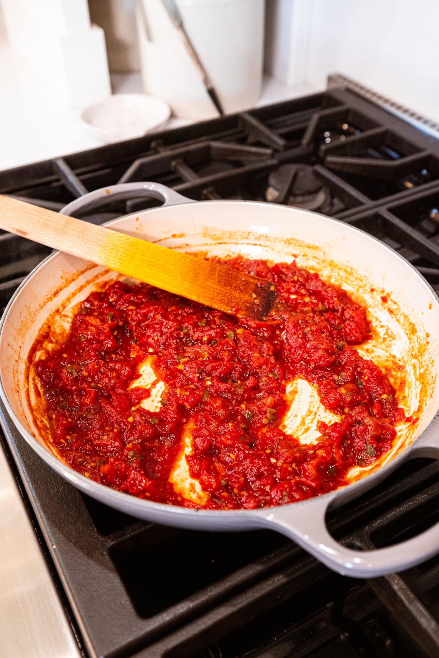 Mixture of tomato jam in a large skillet on the stovetop with cooked down texture.