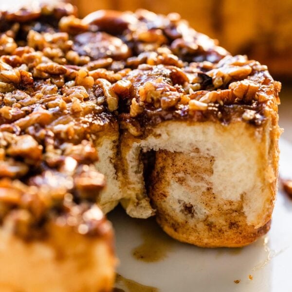 White plate with sticky buns recipe with two rolls missing showing the dough interior of the buns.