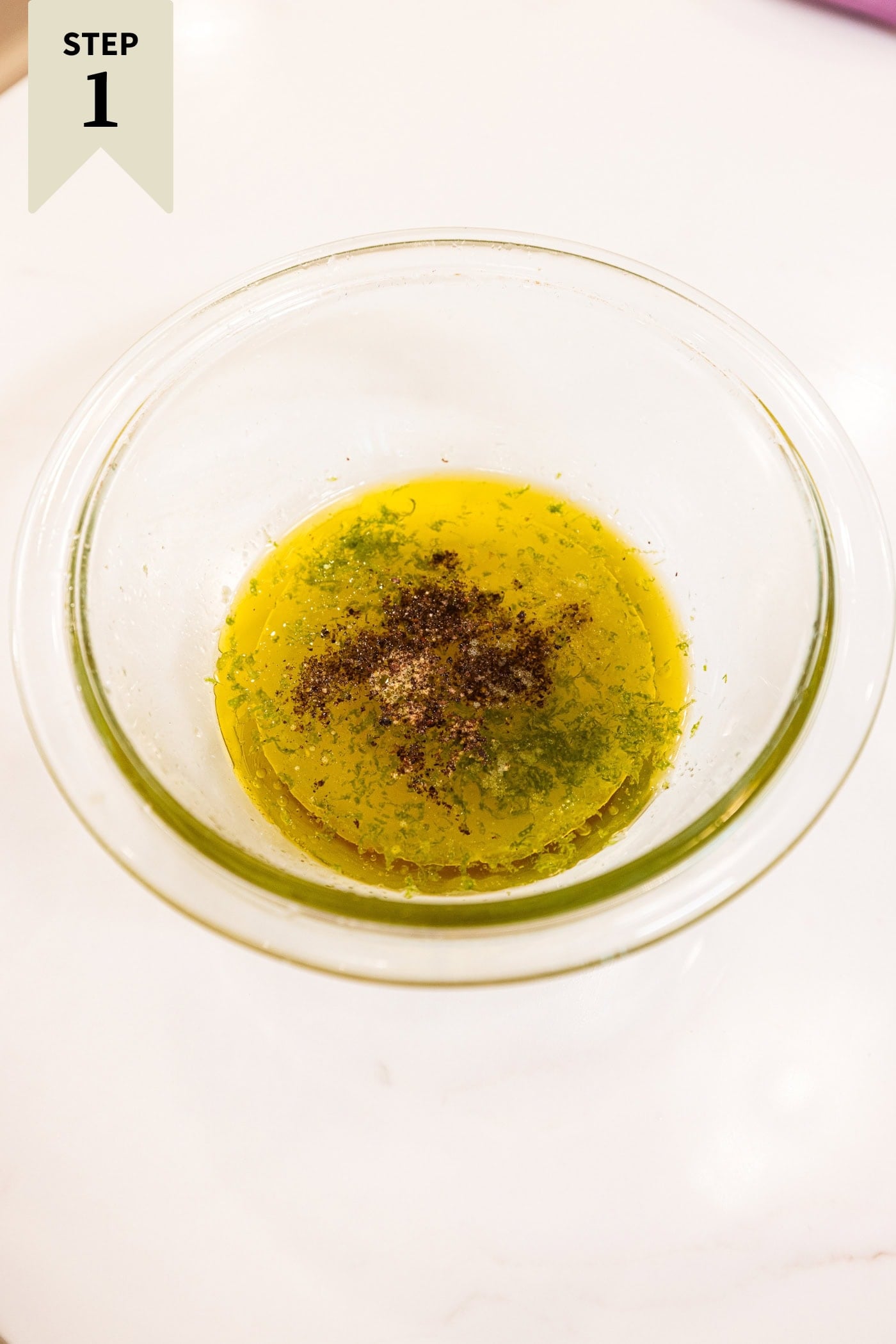 Glass bowl with ingredients needed for a honey and lime dressing to be poured on top of a salad before being mixed together.