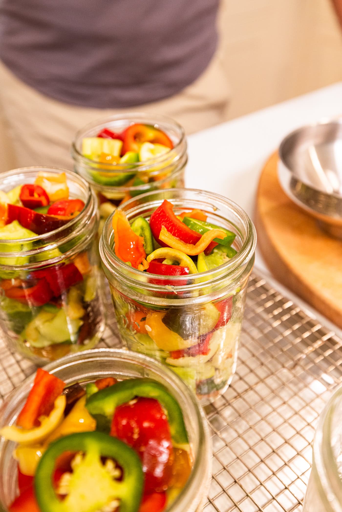 Glass canning jars packed with slices of hot peppers ready for a brine.