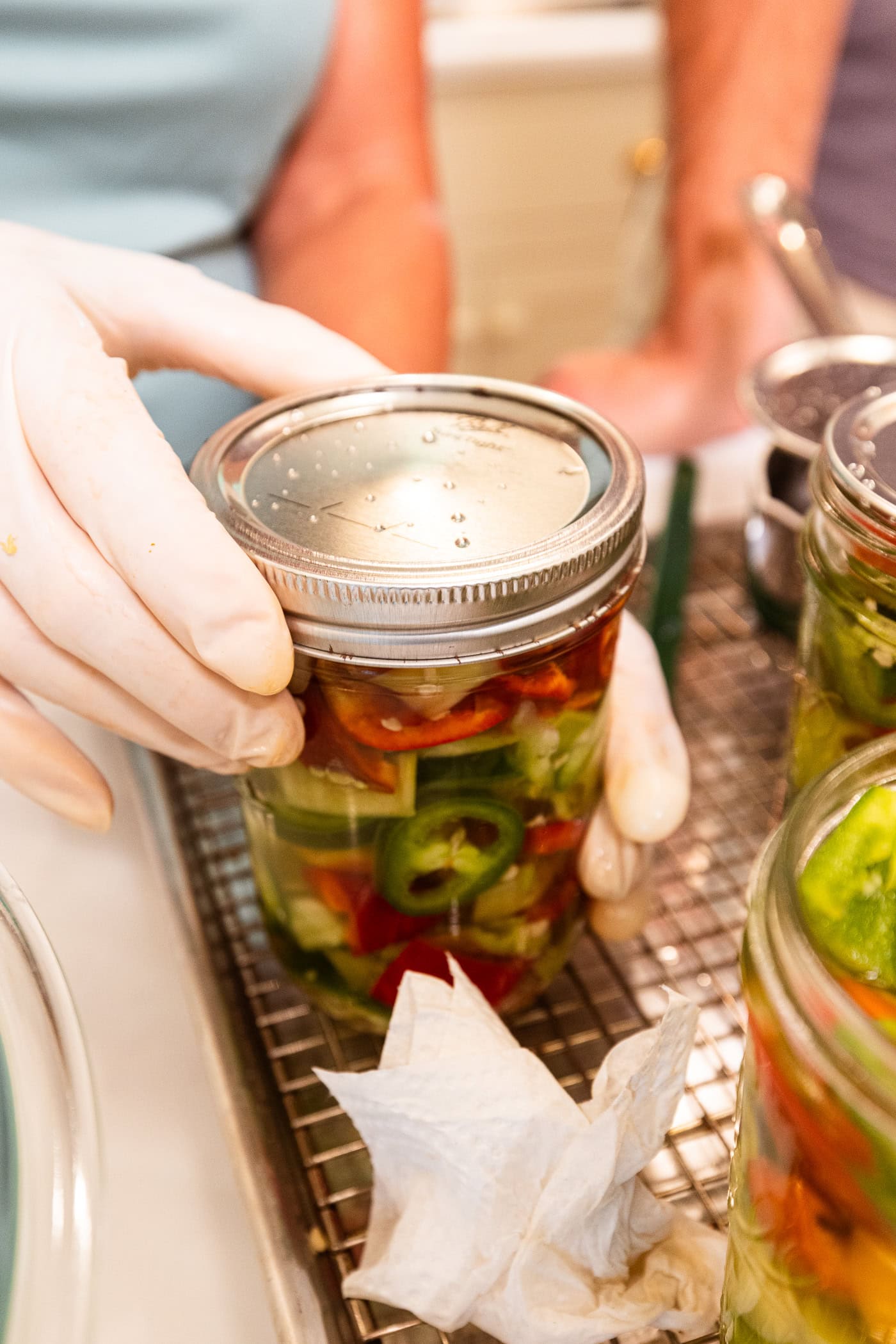 Hand tightening lid and ring for a canning jar filled with peppers before going into the water bath canner.