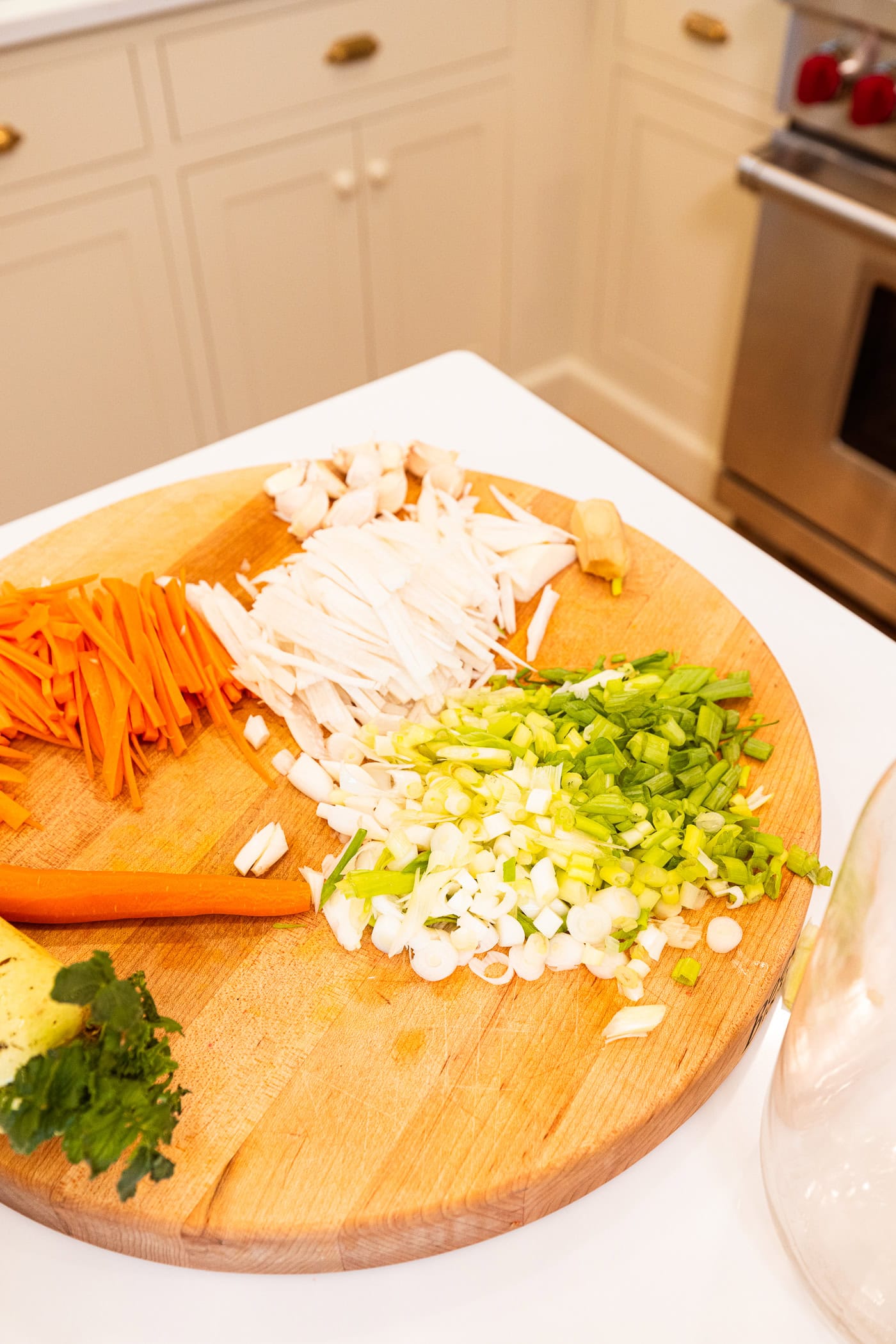 Wooden cutting board with sliced components needed for homemade kimchi.