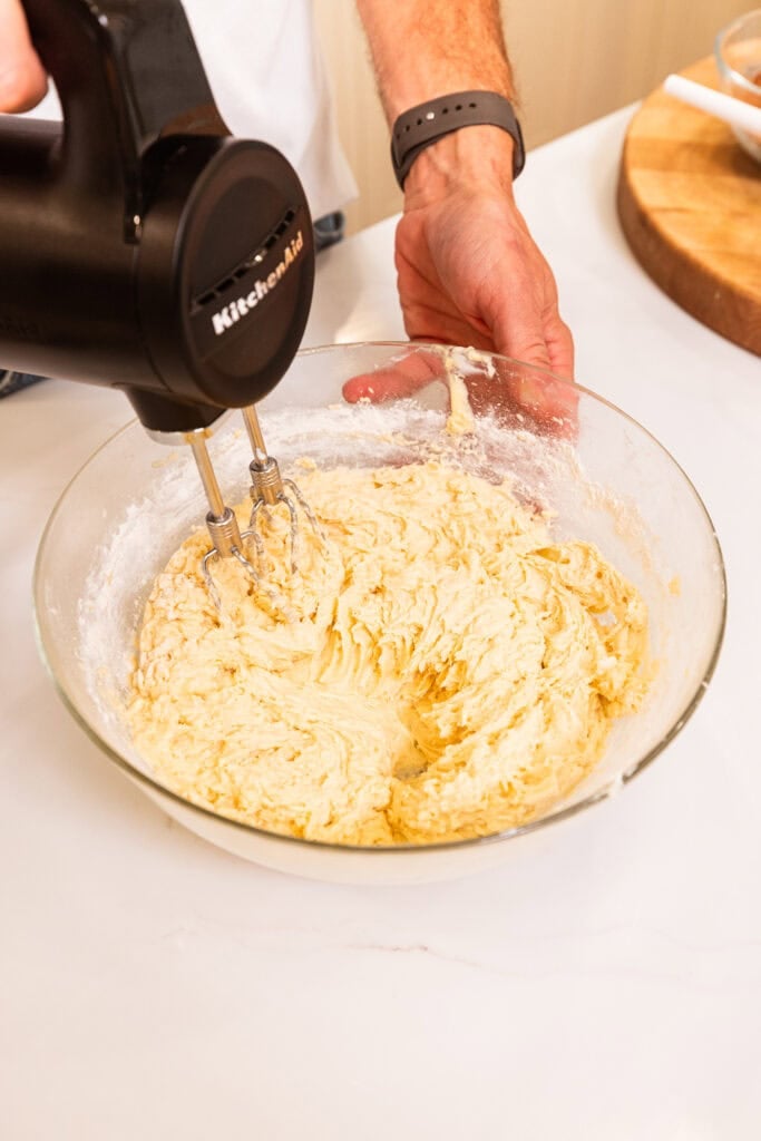 A hand mixer beating ingredients together to form a batter.
