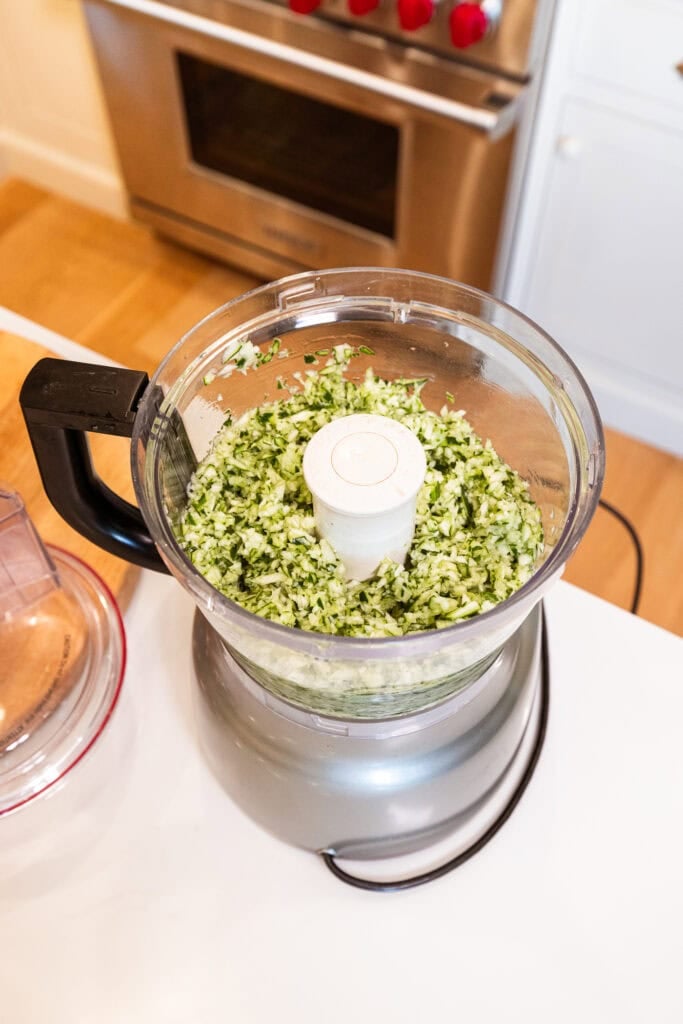 Diced cucumber sits in a food processor.