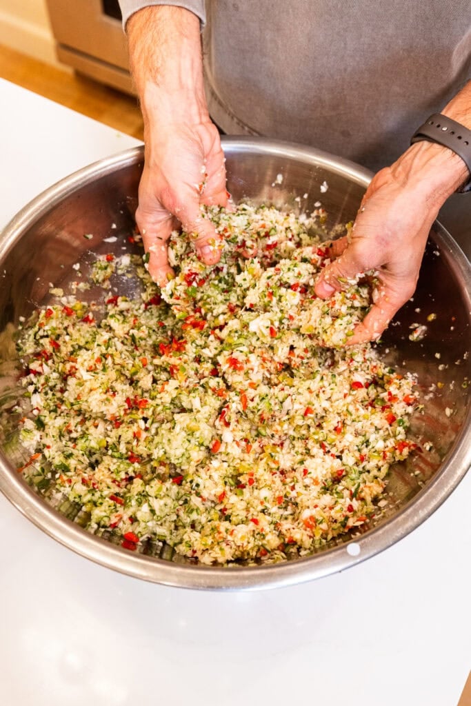 Chopped vegetables get mixed together in a bowl.
