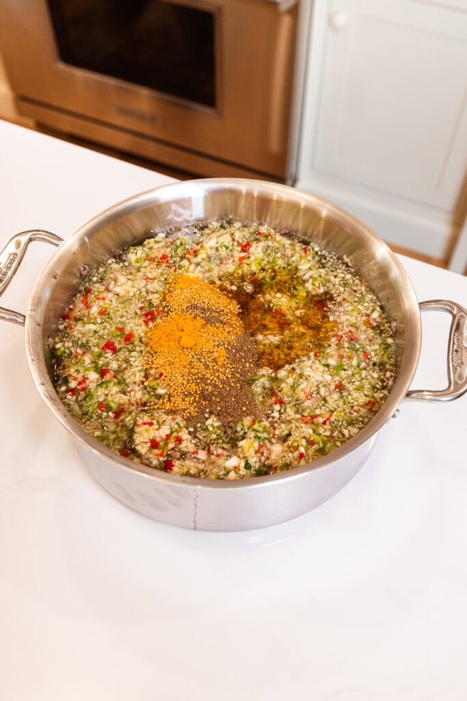 Spices sit in a brine with chopped vegetables ready to be mixed.