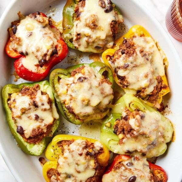 Large white serving platter with stuffed peppers with melted cheese on top.